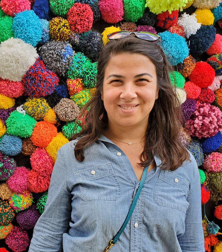 Smiling woman stands in front of colorful background