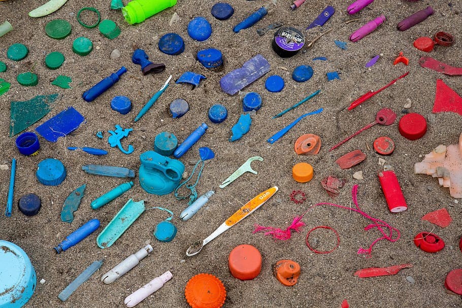 Plastic bits arranged by color on the sand.
