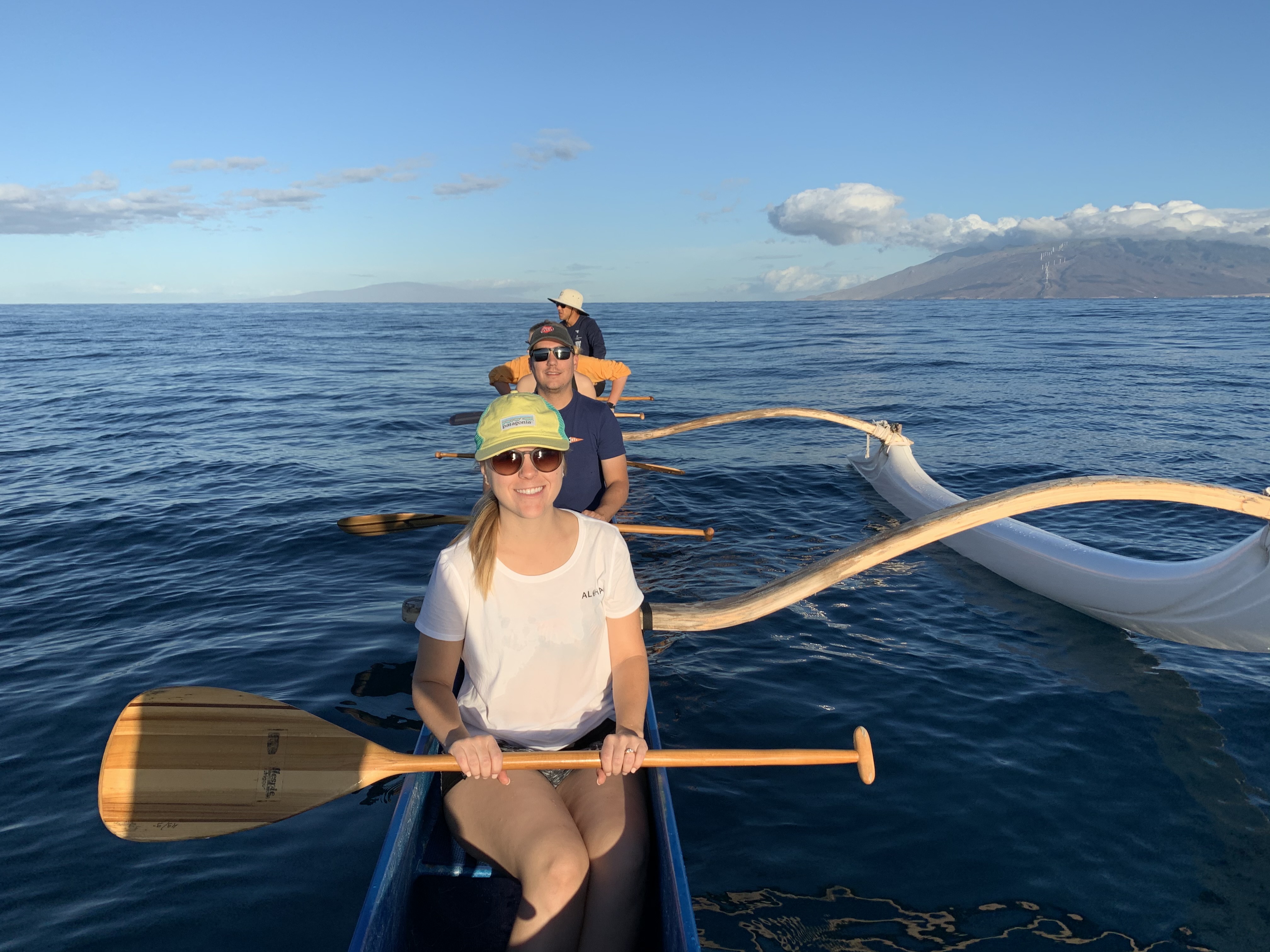 Woman and two men canoeing in ocean