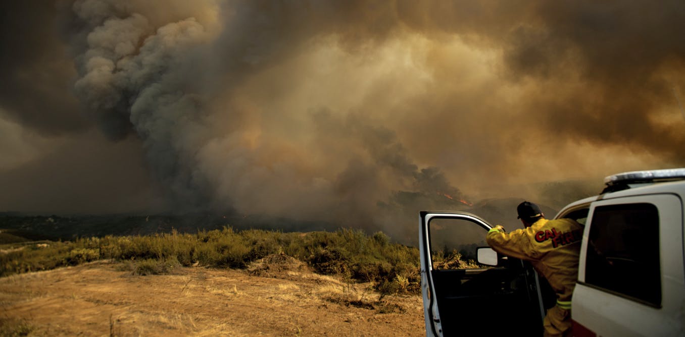 Cal Fire Division Chief Mark Higgins directs helicopters dropping water in Lakeport, California. Photo Credit: AP Photo/Noah Berger
