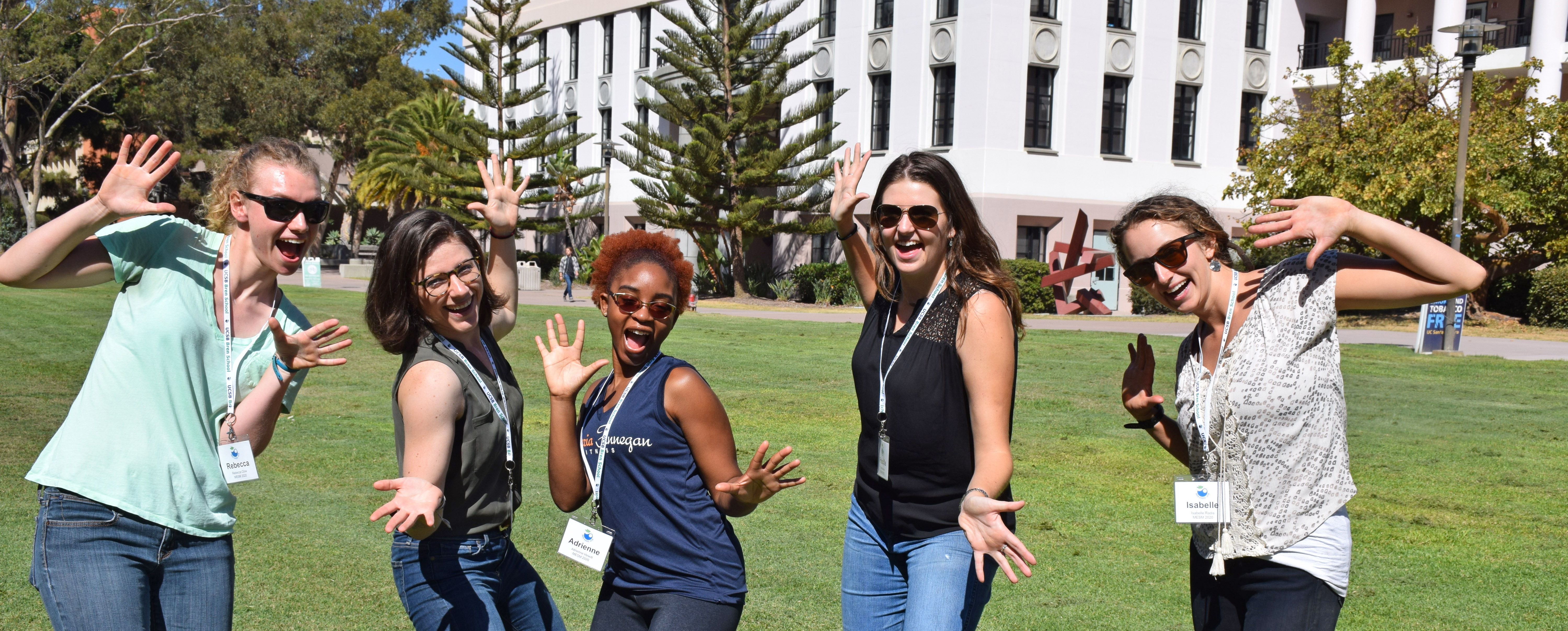 Five students make funny poses on lawn