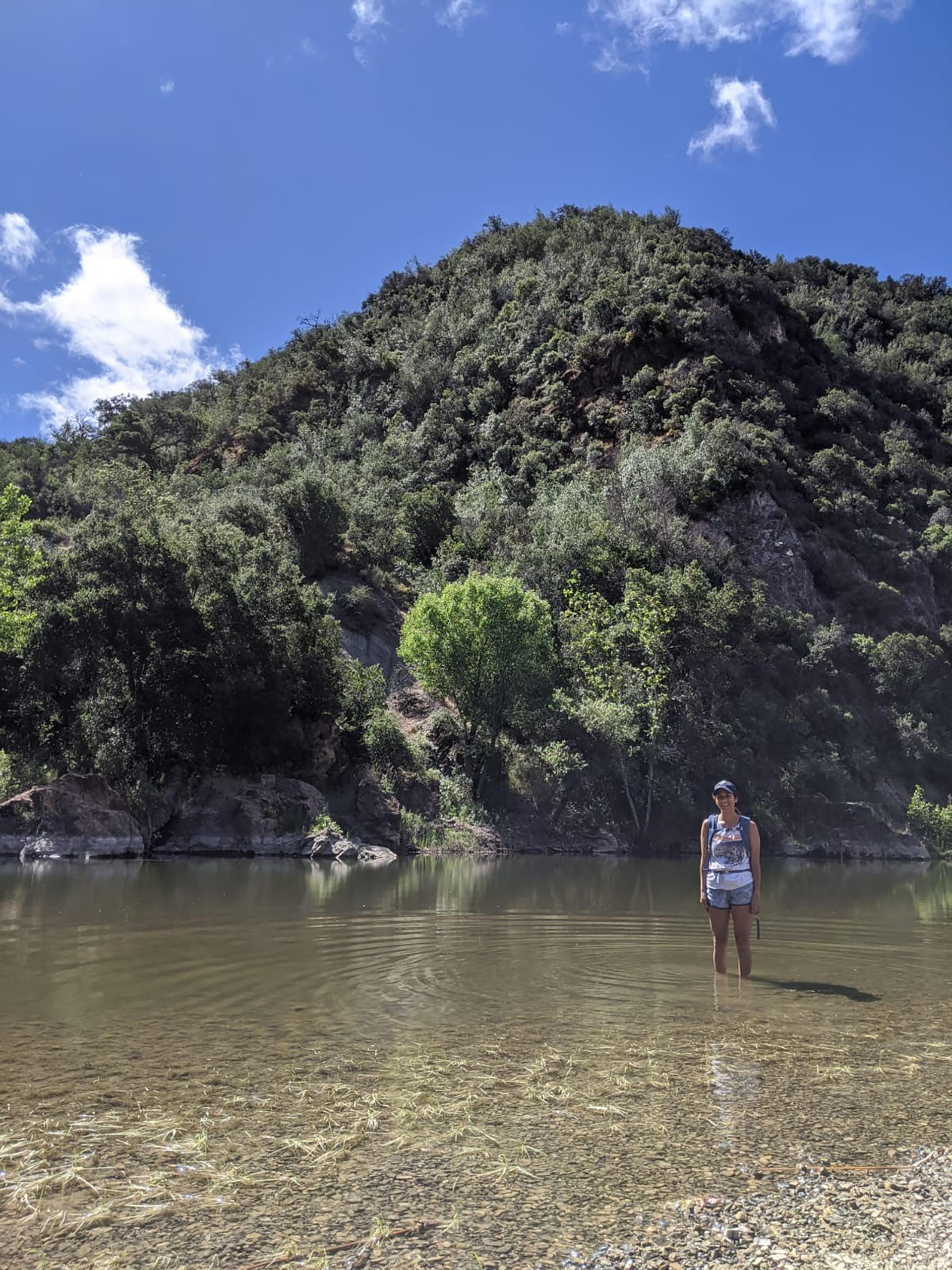 Woman in backpack standing in shallow river