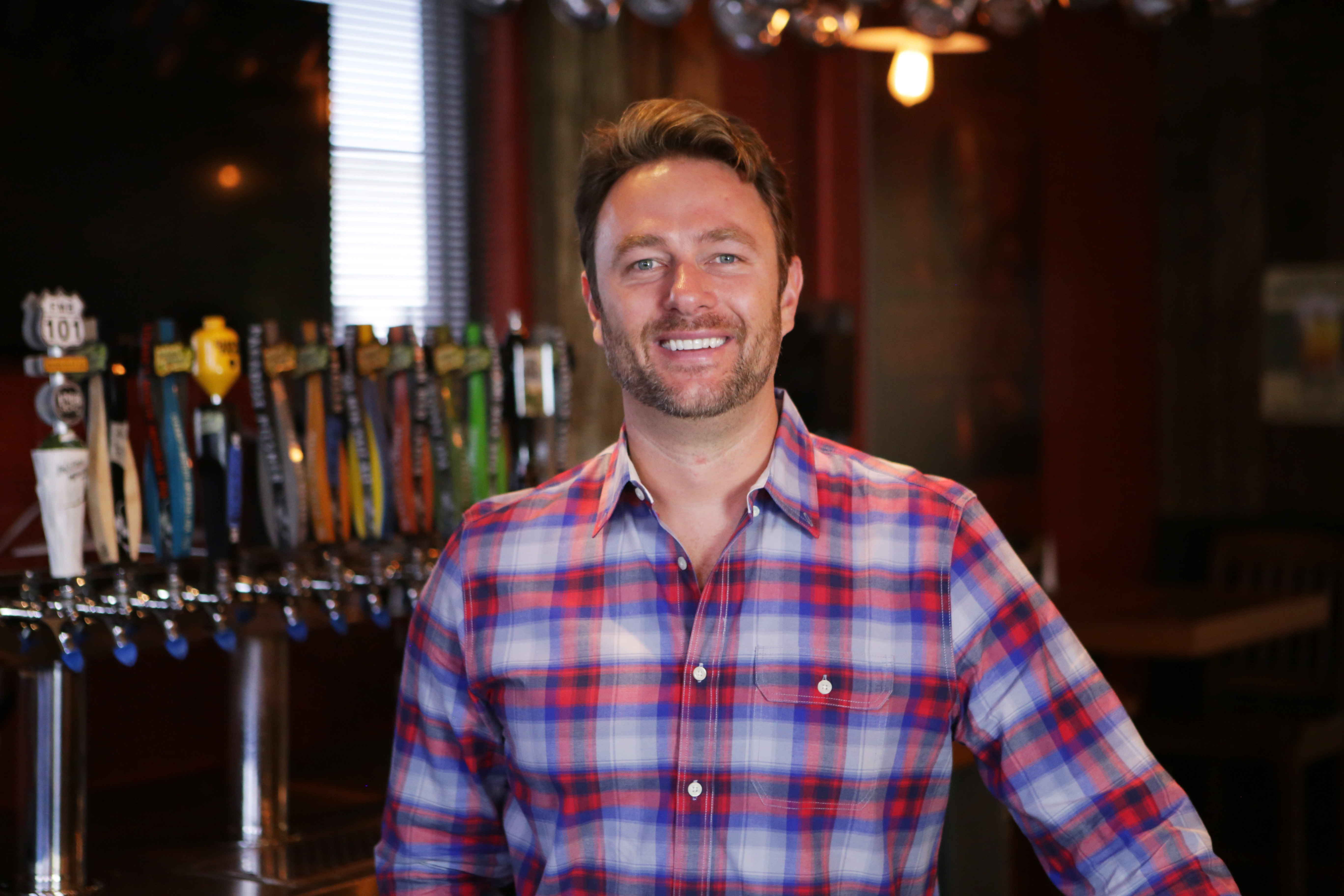 Smiling man in front of a beer tap