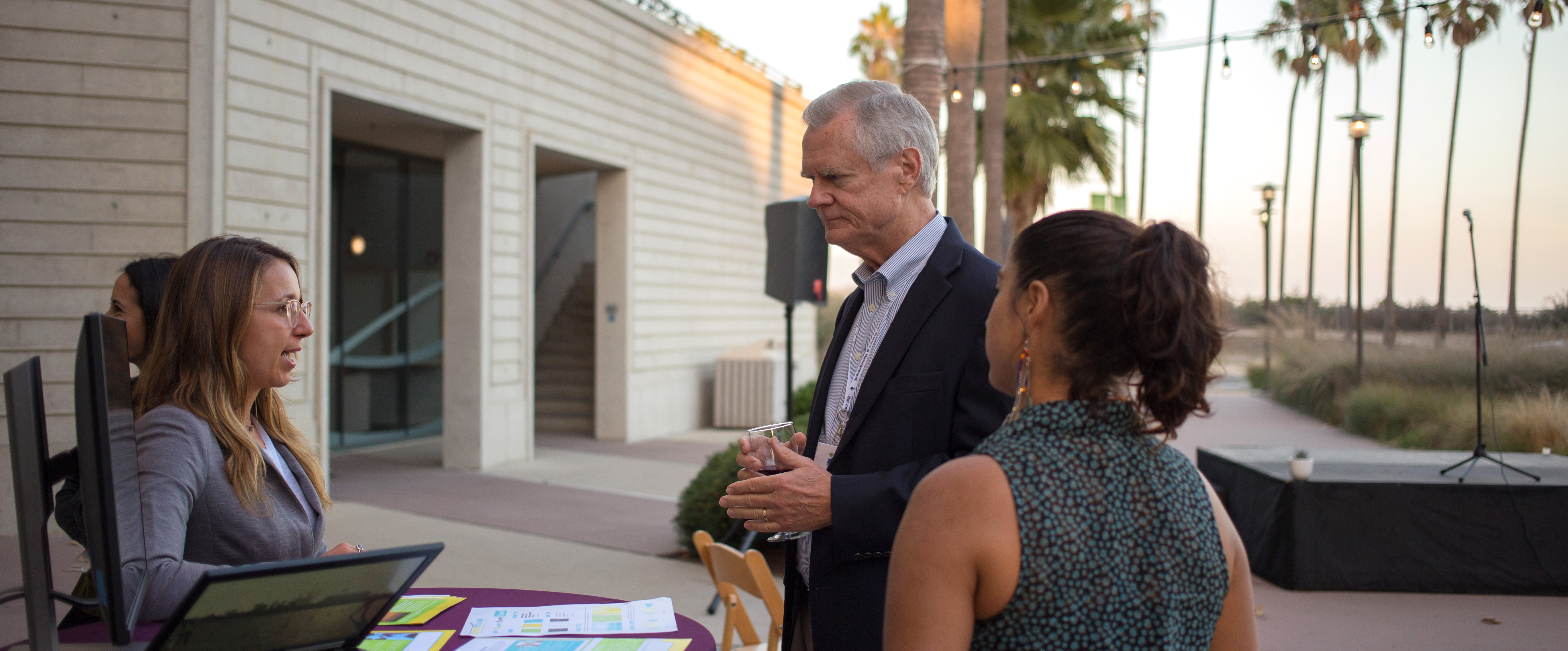 Woman talking to man and woman at a table with flyers