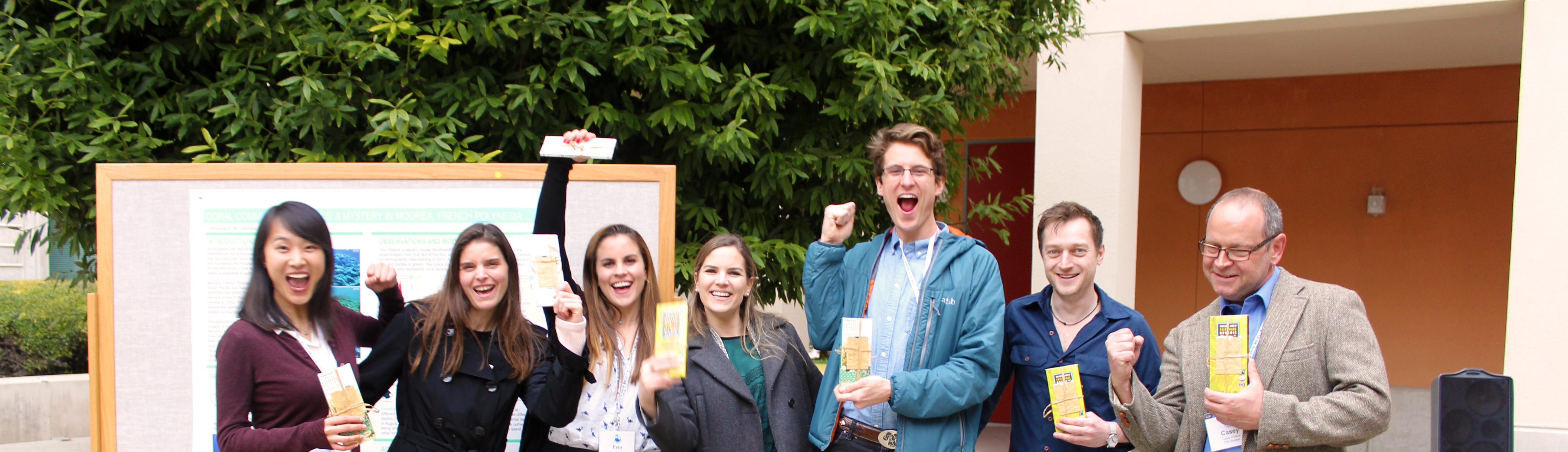 Group of cheering students standing in front of a poster