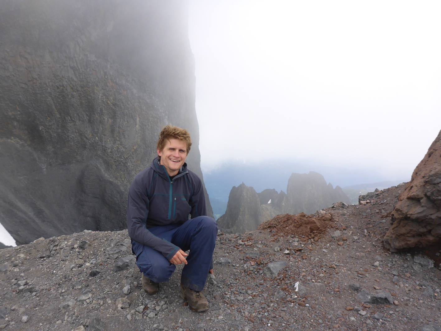 David Williams kneels on a foggy cliff