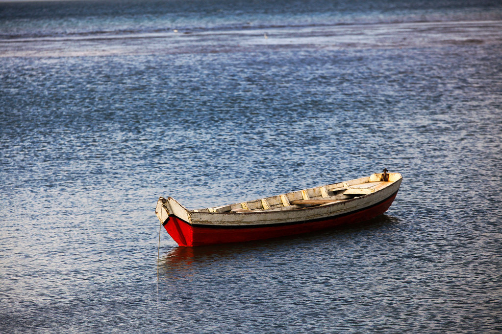 Small fishing boat floats unattended in ocean.