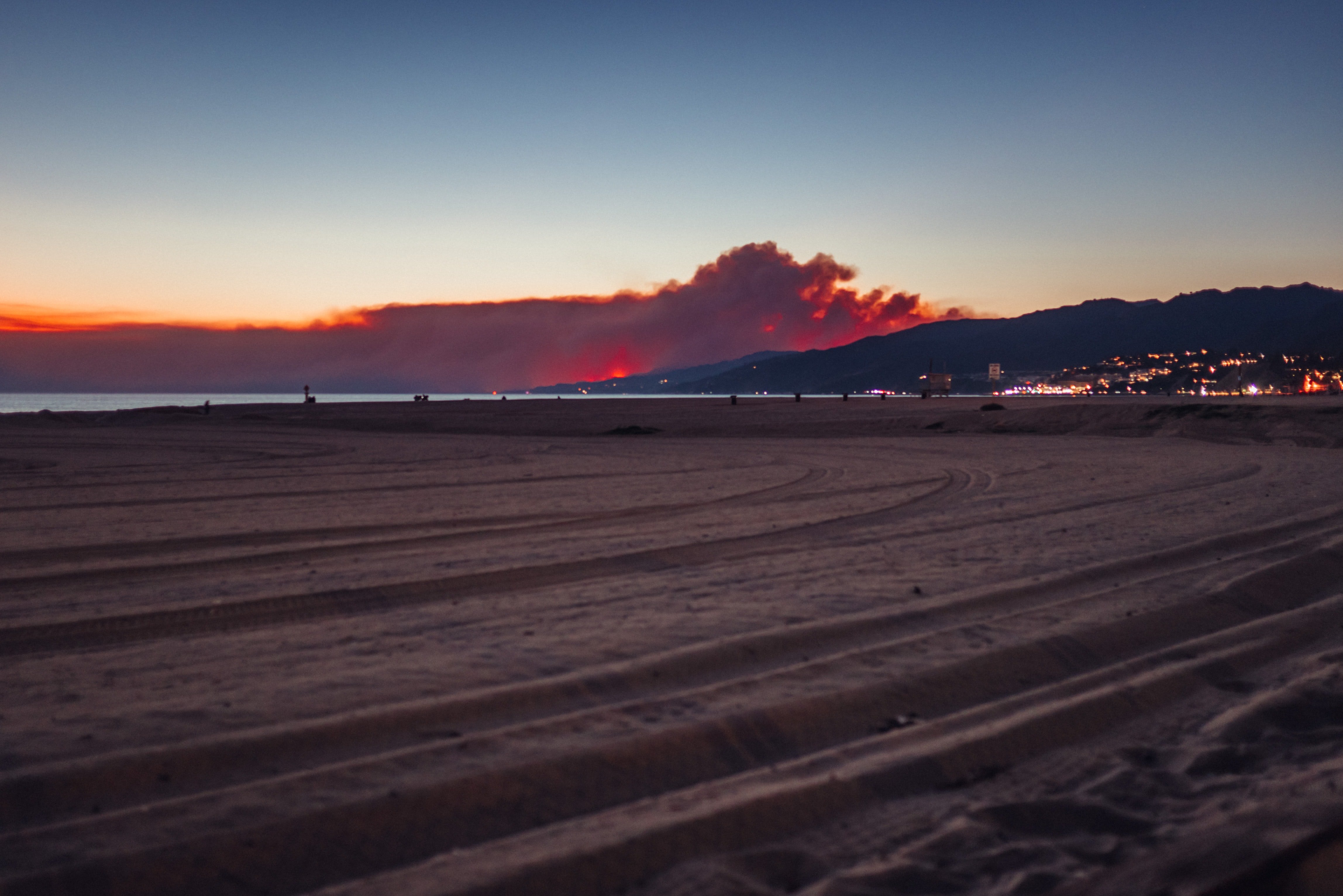 Wildfire smoke looms over hills of a seaside town