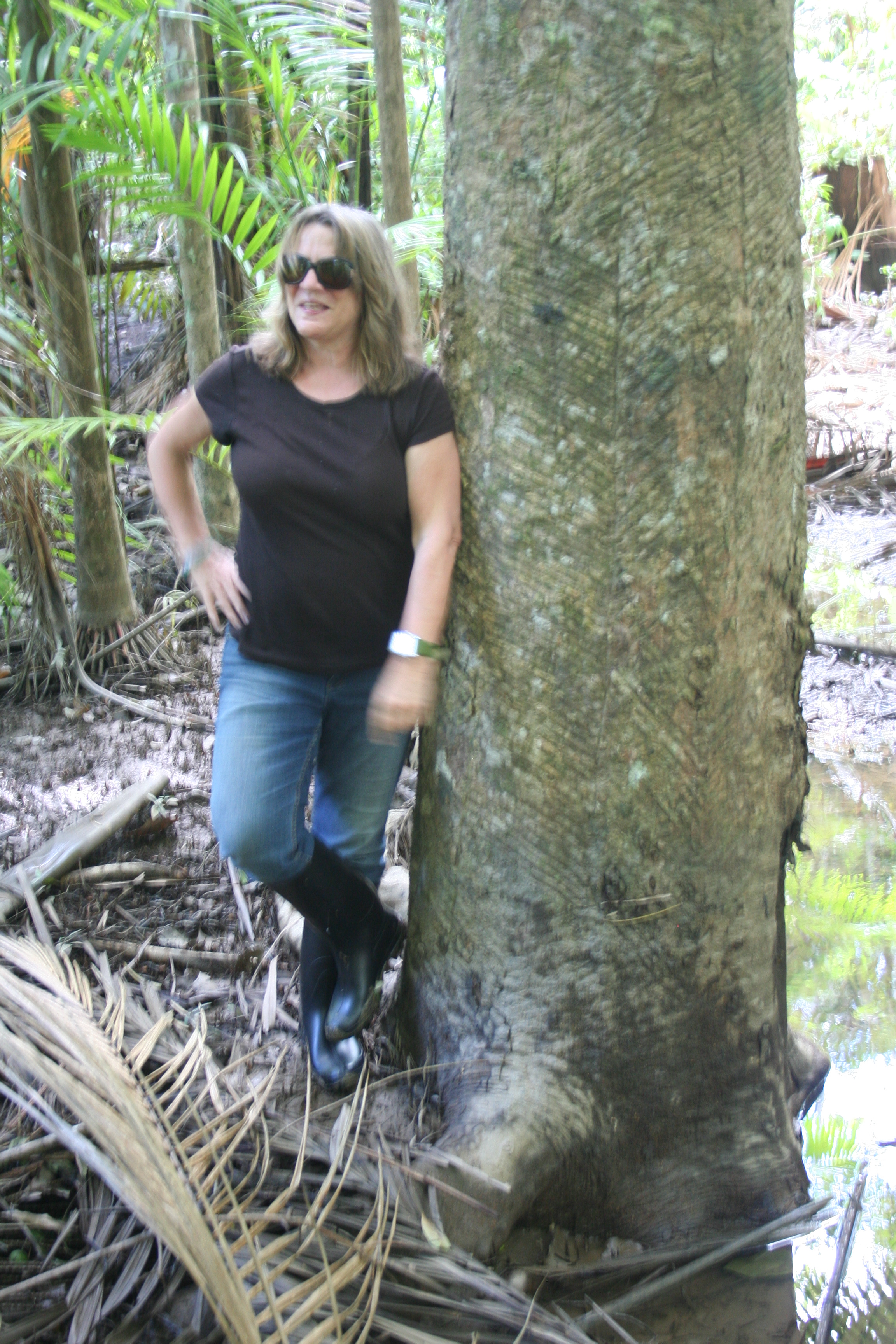 Susanna Hecht leans against a large tree trunk