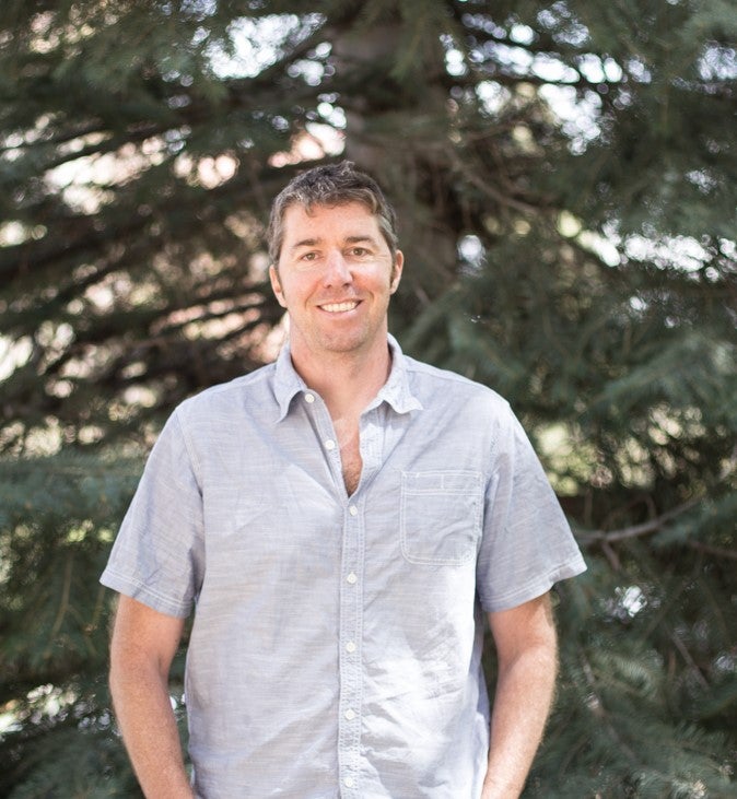 Noah Fierer stand in front of pine trees