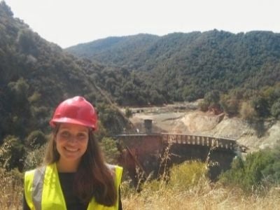 Woman in hardhat with San Clemente dam in background