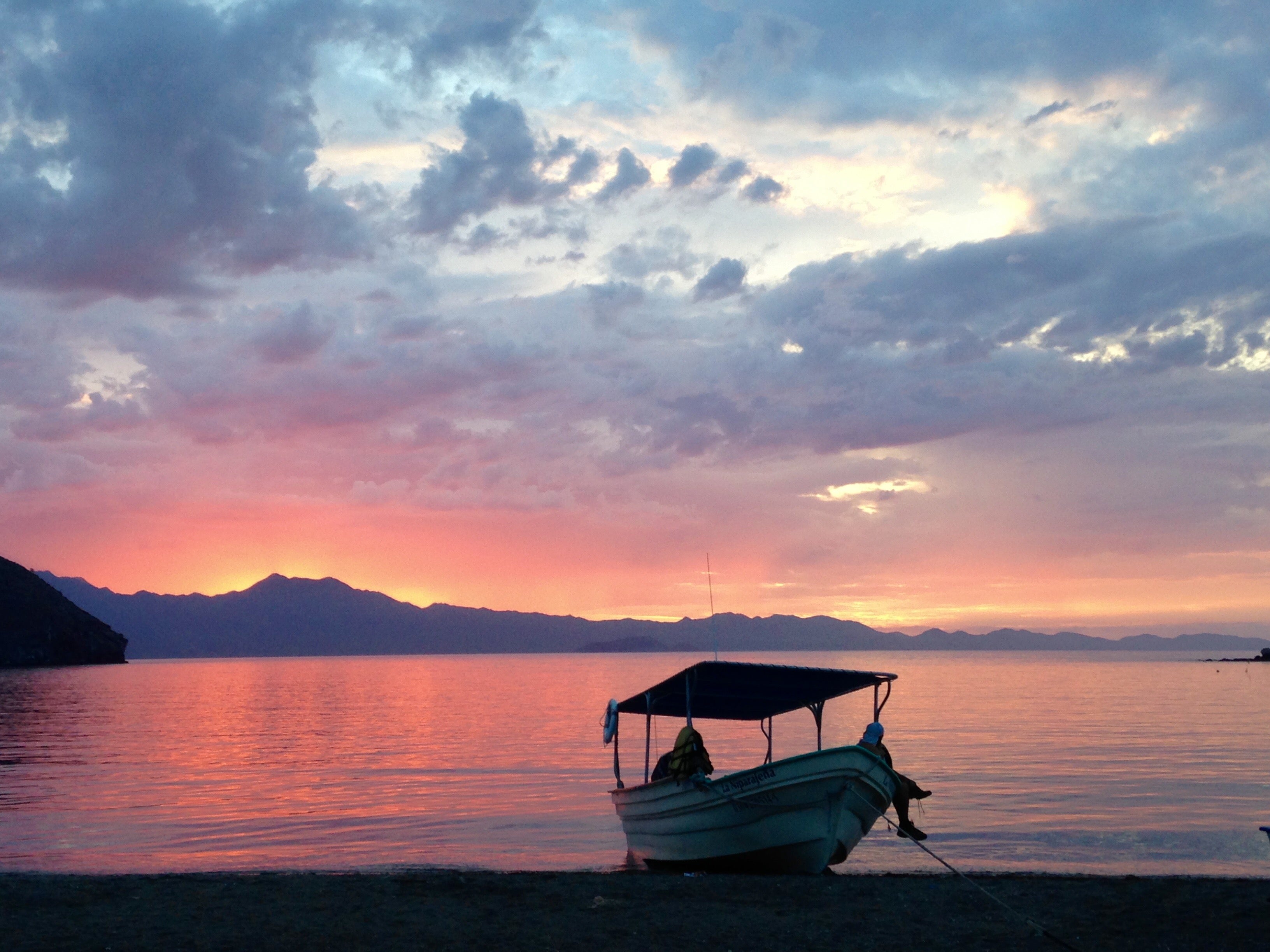 Panga fishing boat on water during sunset