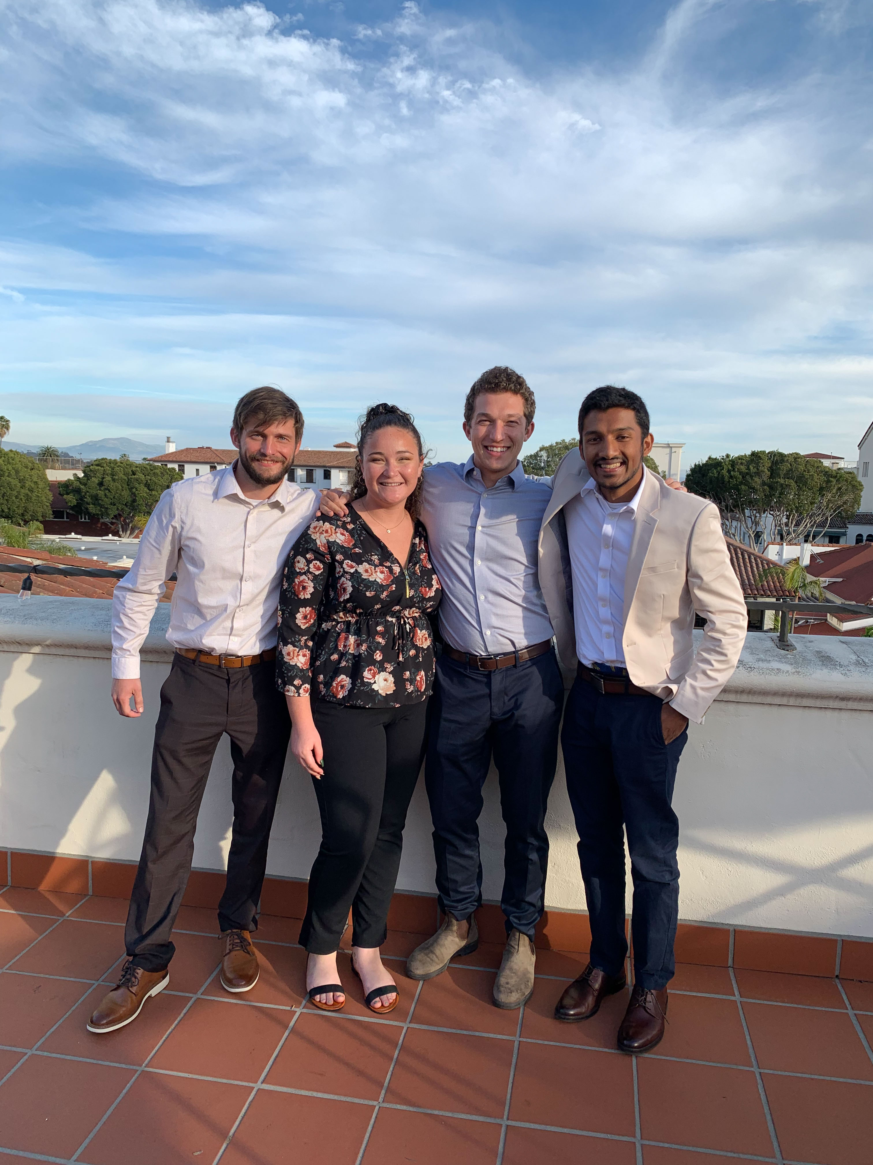 Group of four students pose together in celebration