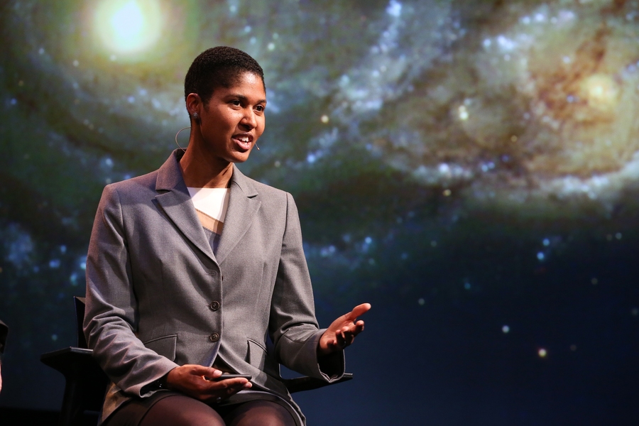 Woman standing on stage giving a talk with space background