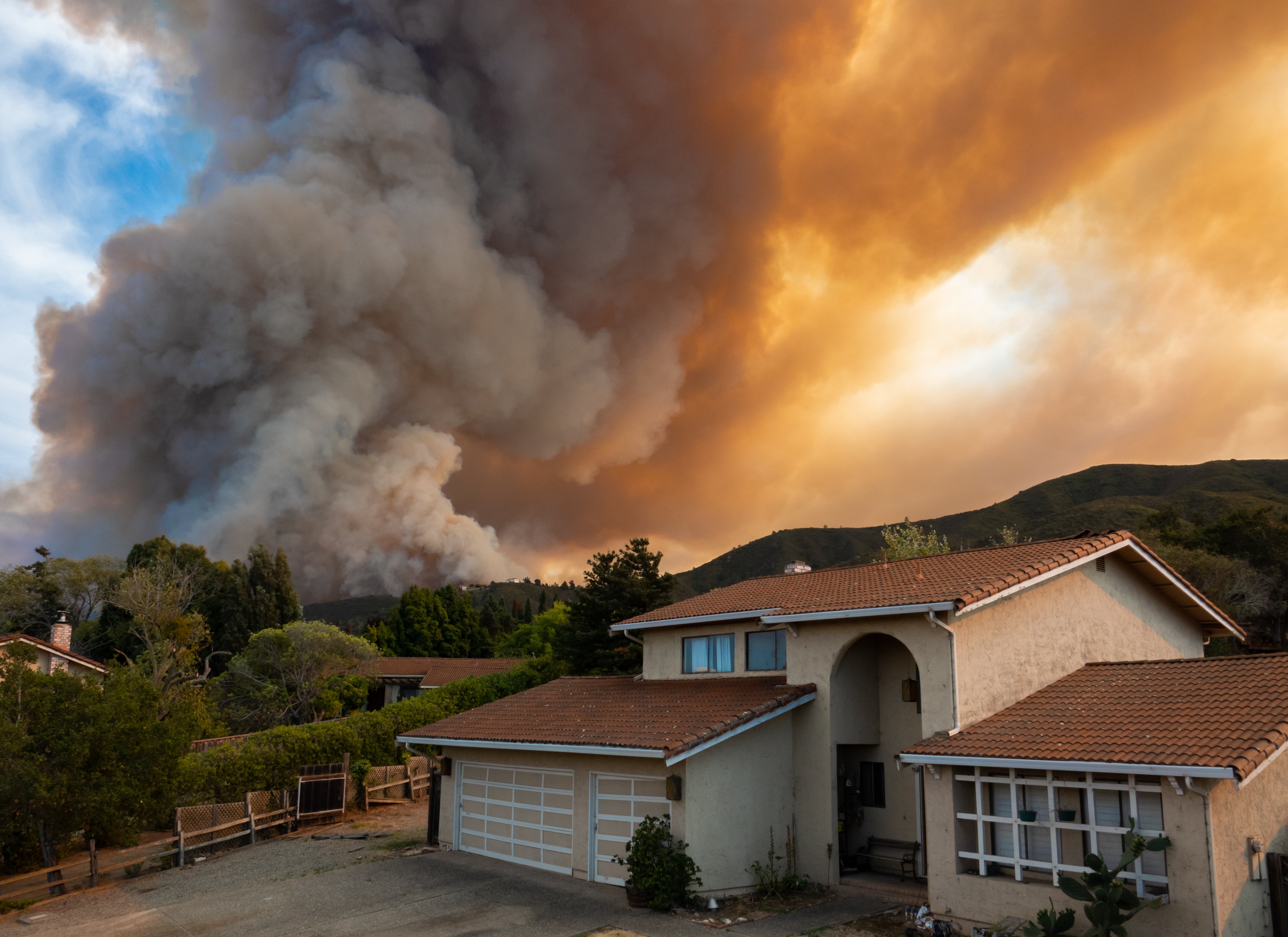Plume of wildfire smoke in sky above housing area