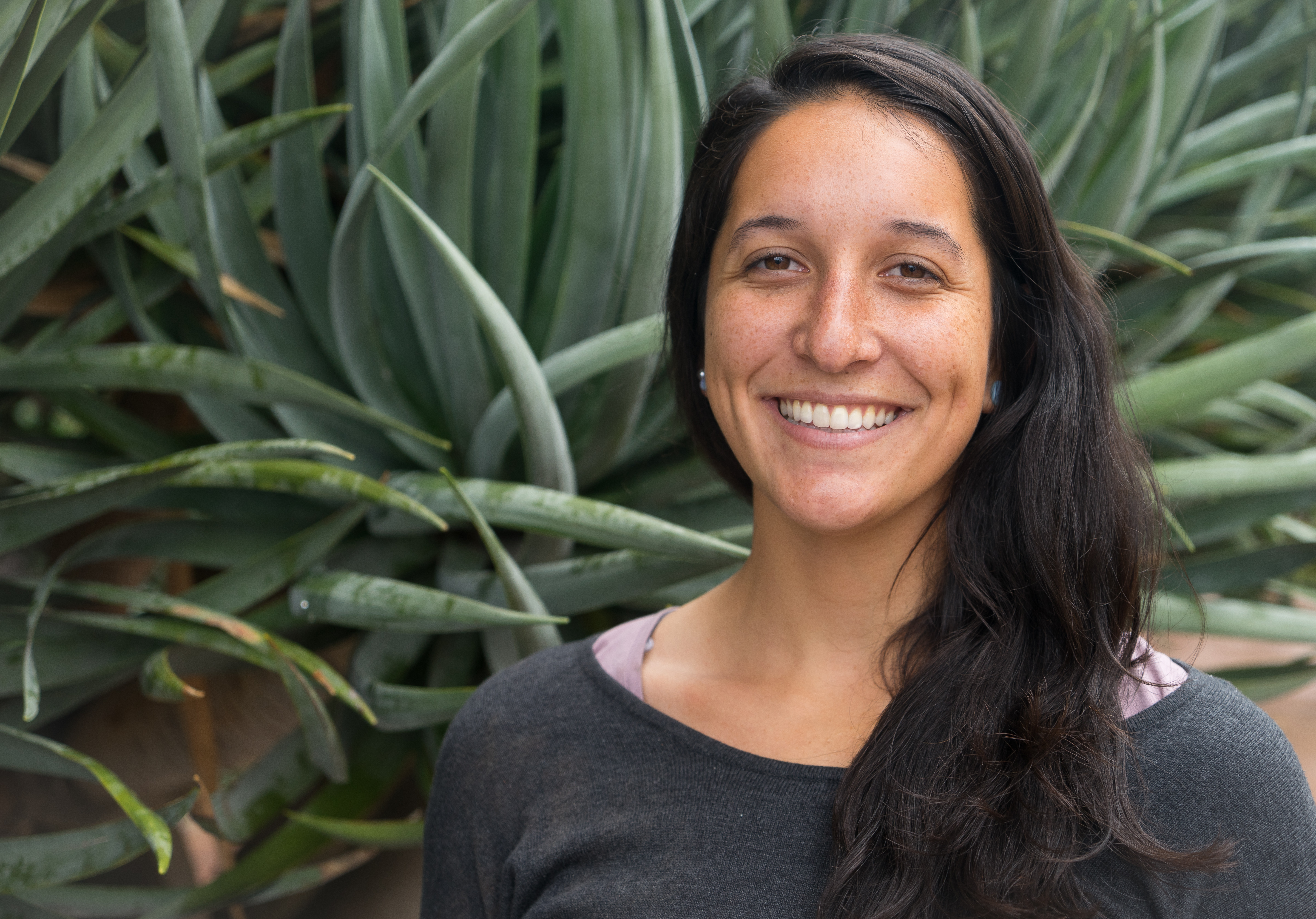 Woman's headshot in front of green foliage