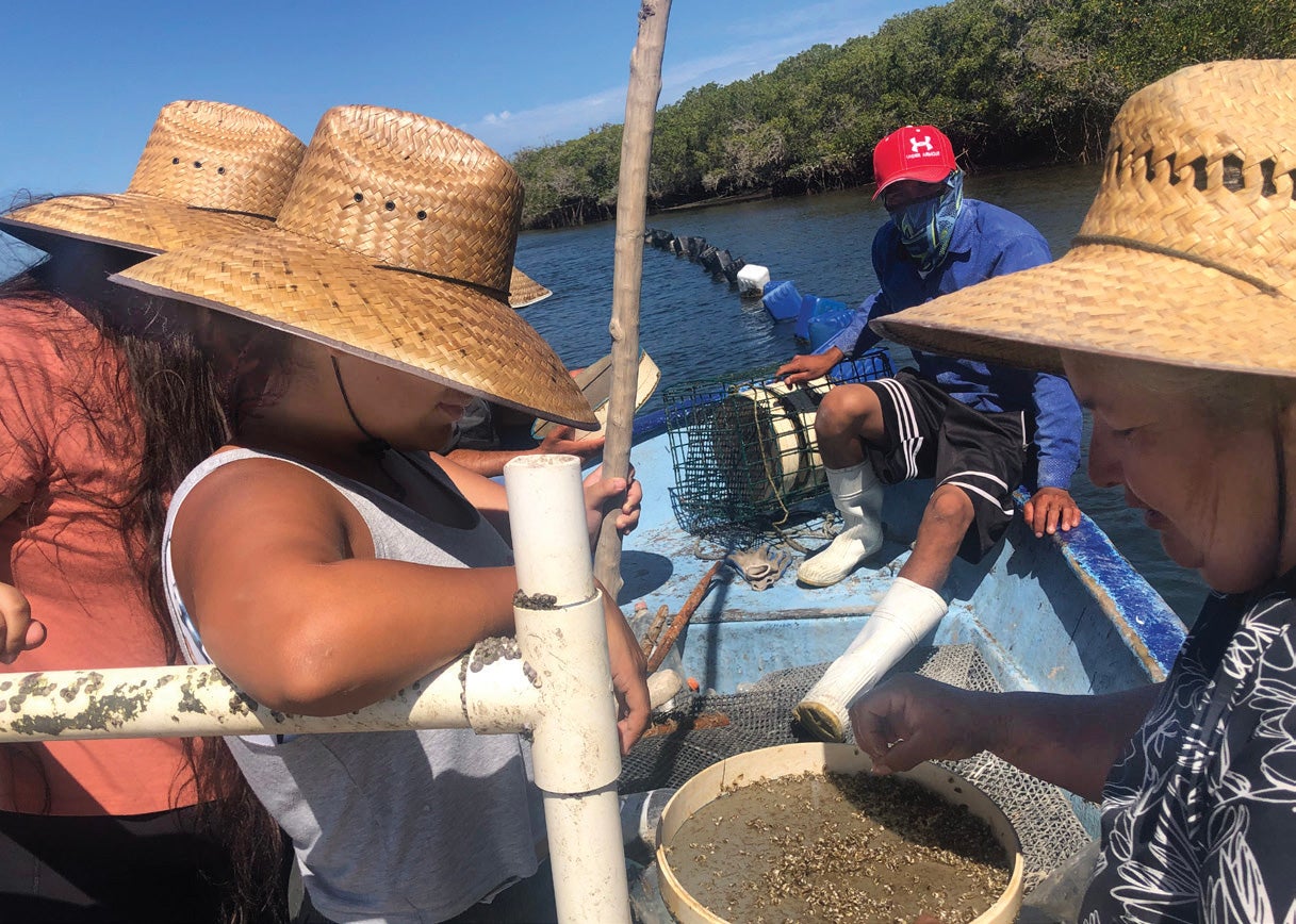 Foreground of fishermen in small motorboat wearing a straw hat. Captain in background