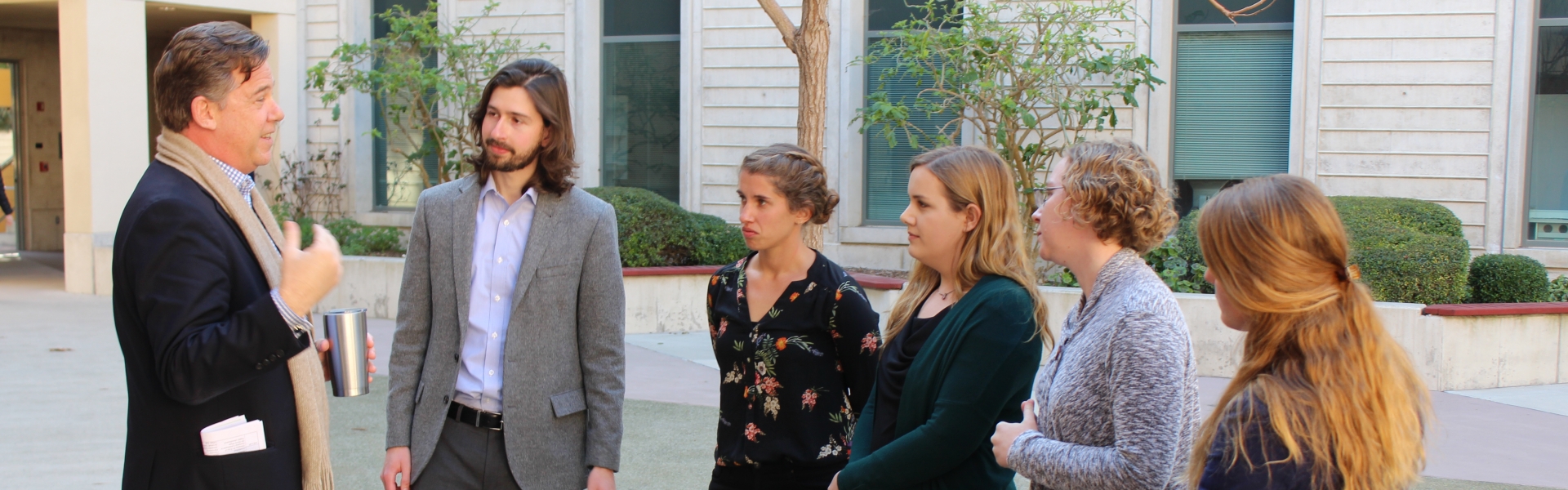 Man speaking to group of students outdoors