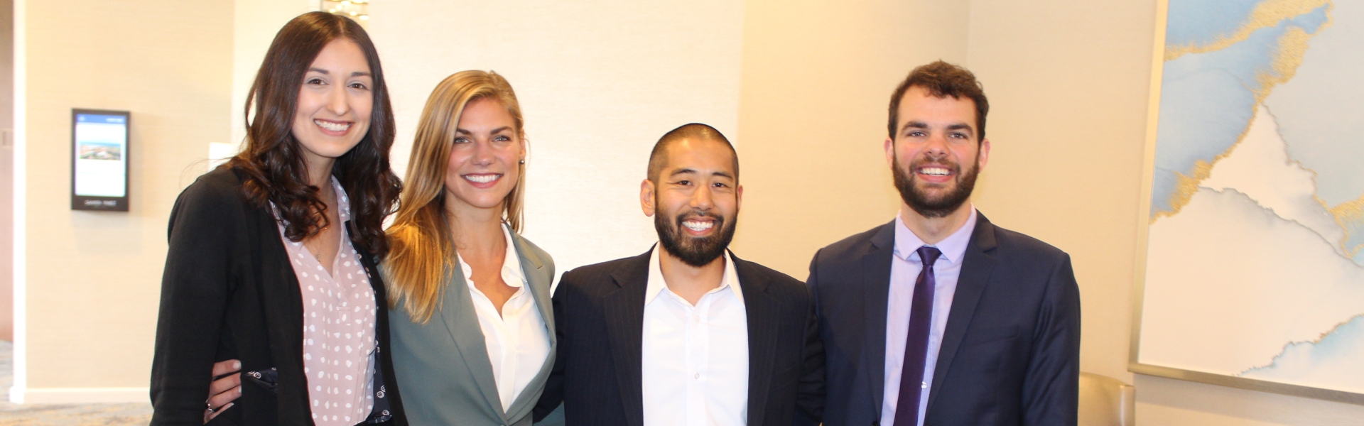 four people standing together smiling 