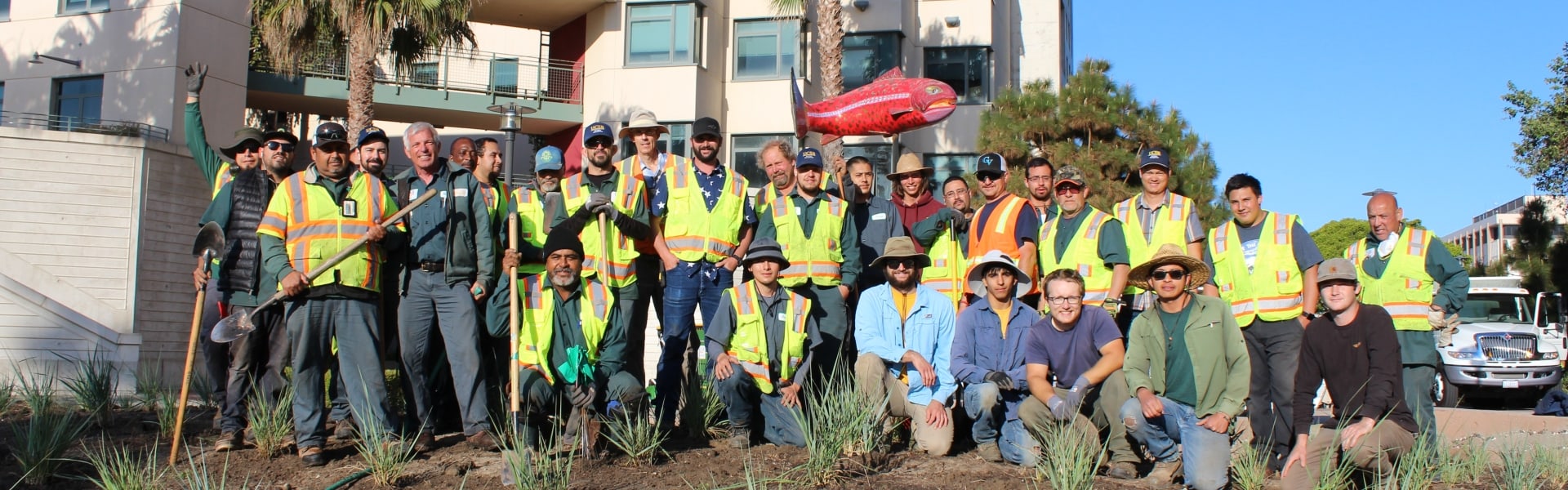 Many people in a landscape crew pose in front of an office building