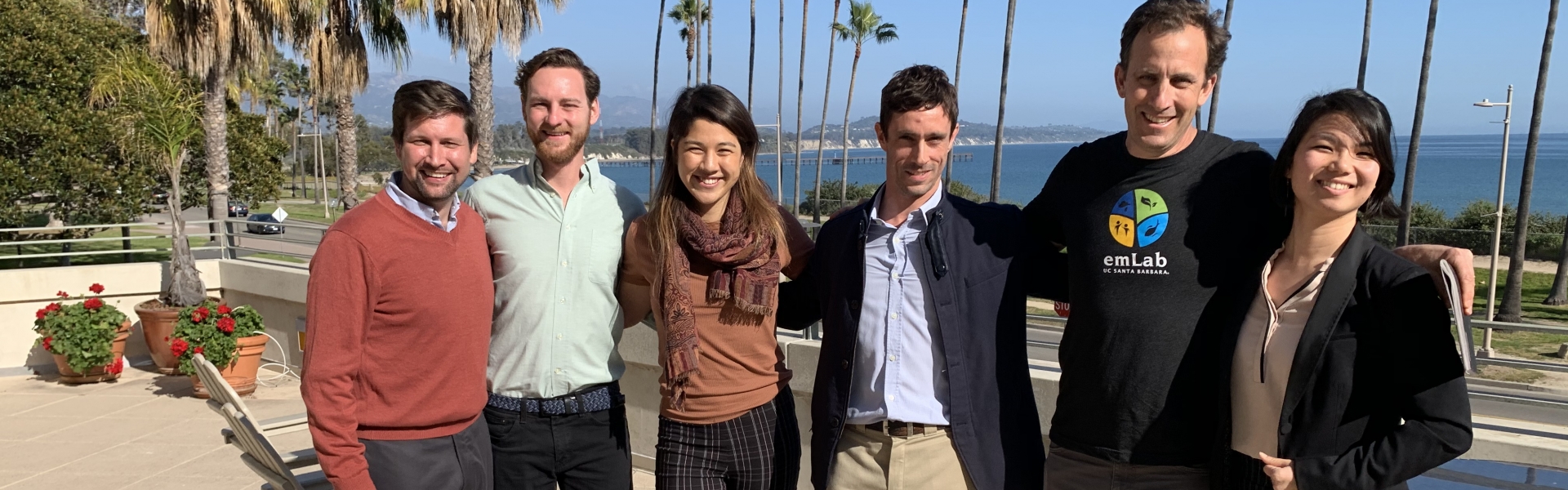 Five students stand with professor in group on terrace overlooking ocean