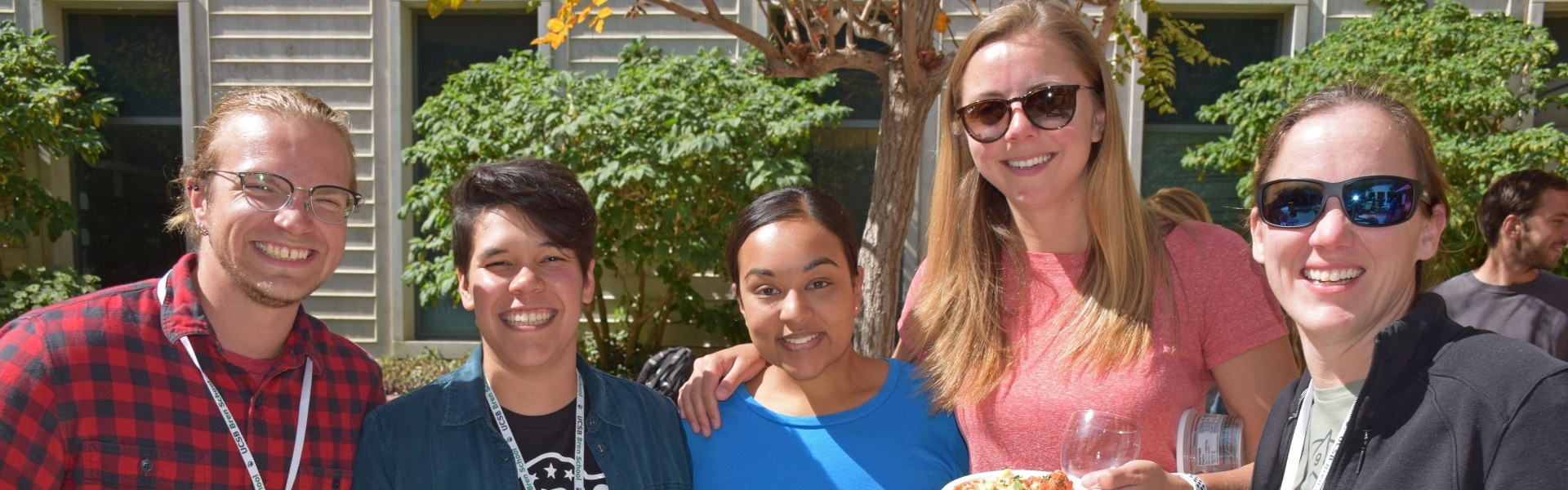 Five students hanging out in sunny courtyard