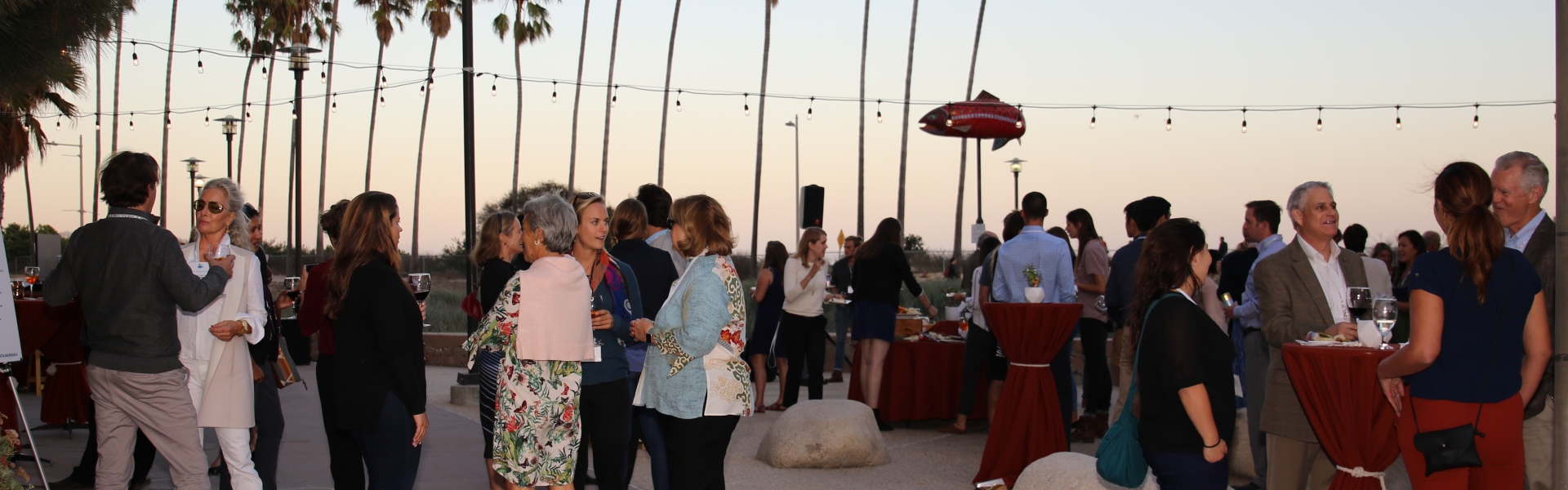 Sunset on a patio with palm trees and crowd of people