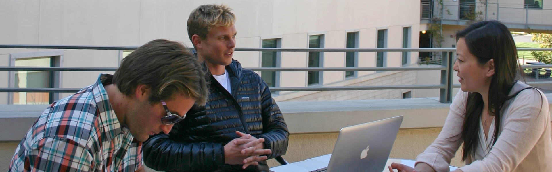 Two students with laptops having discussion with advisor