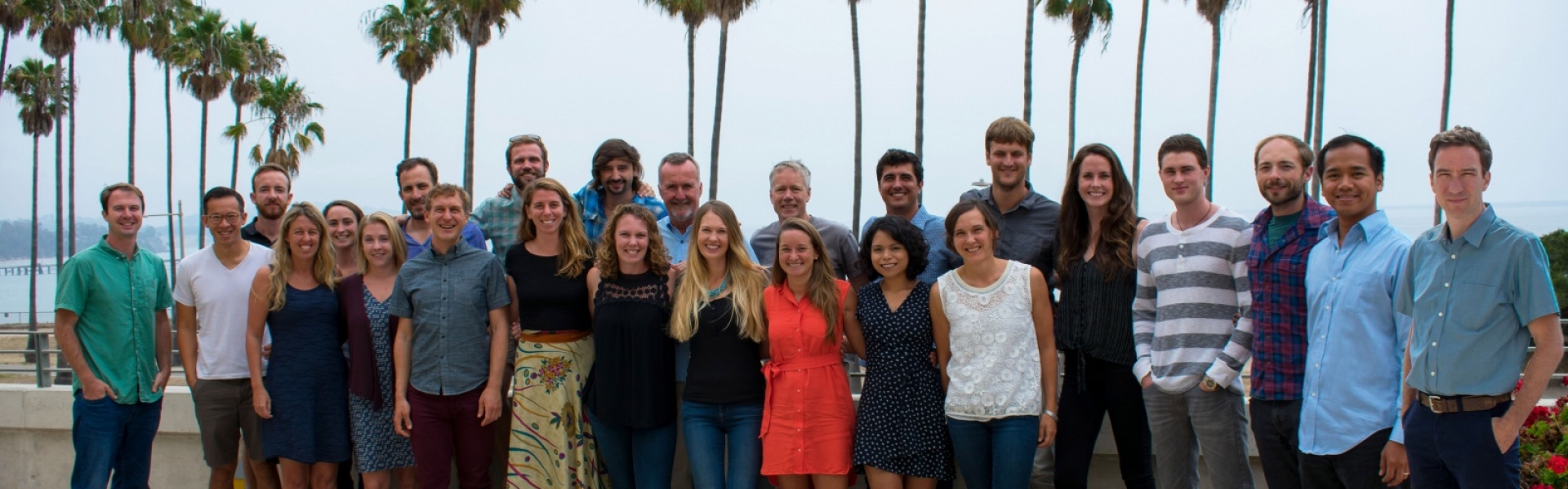 Large group of people pose together on a terrace overlooking ocean