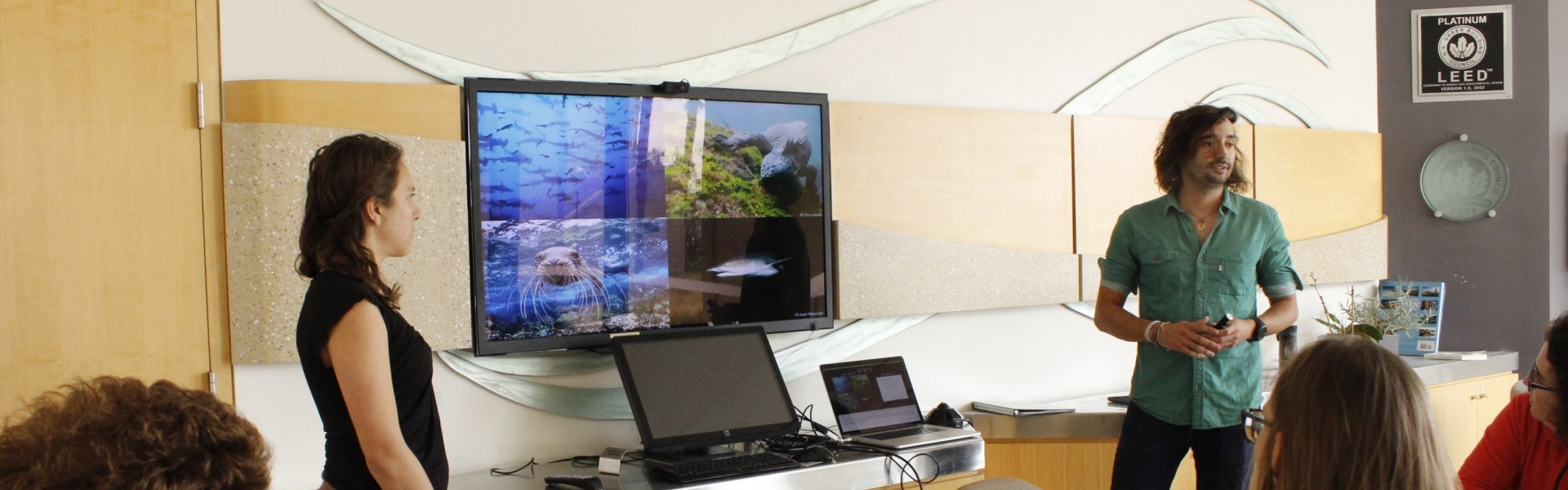 Two people stand by screen showing ocean images