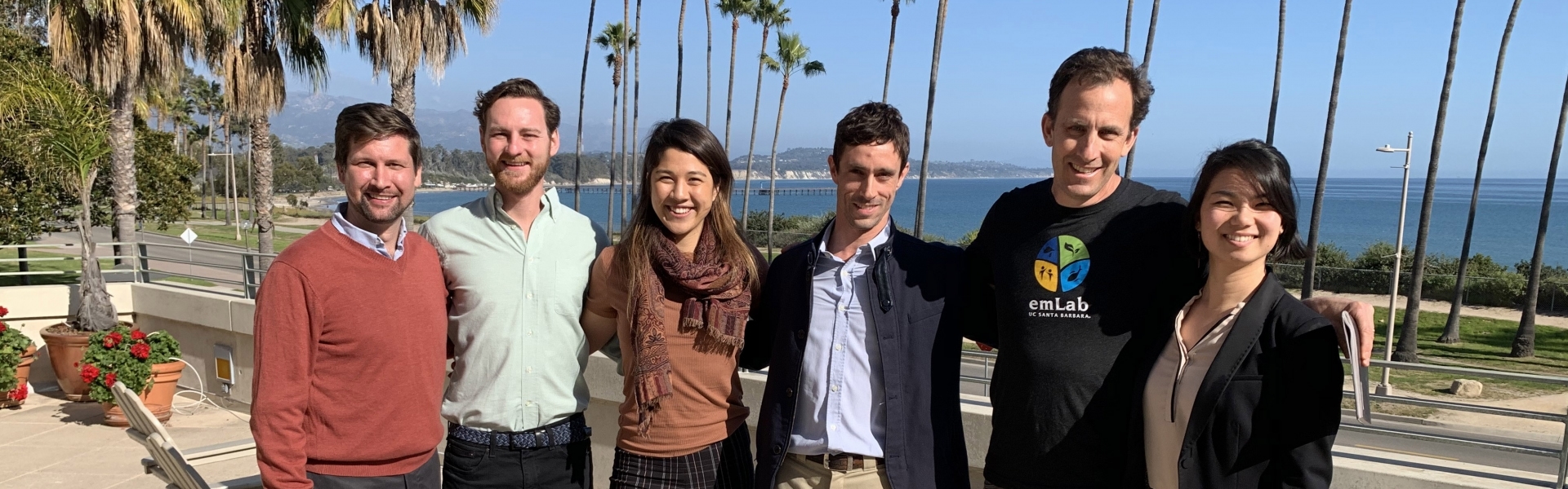 Five students stand with professor in group on terrace overlooking ocean