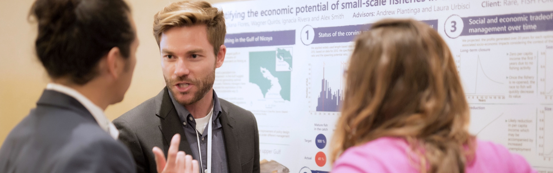 Student discussing his poster with two people