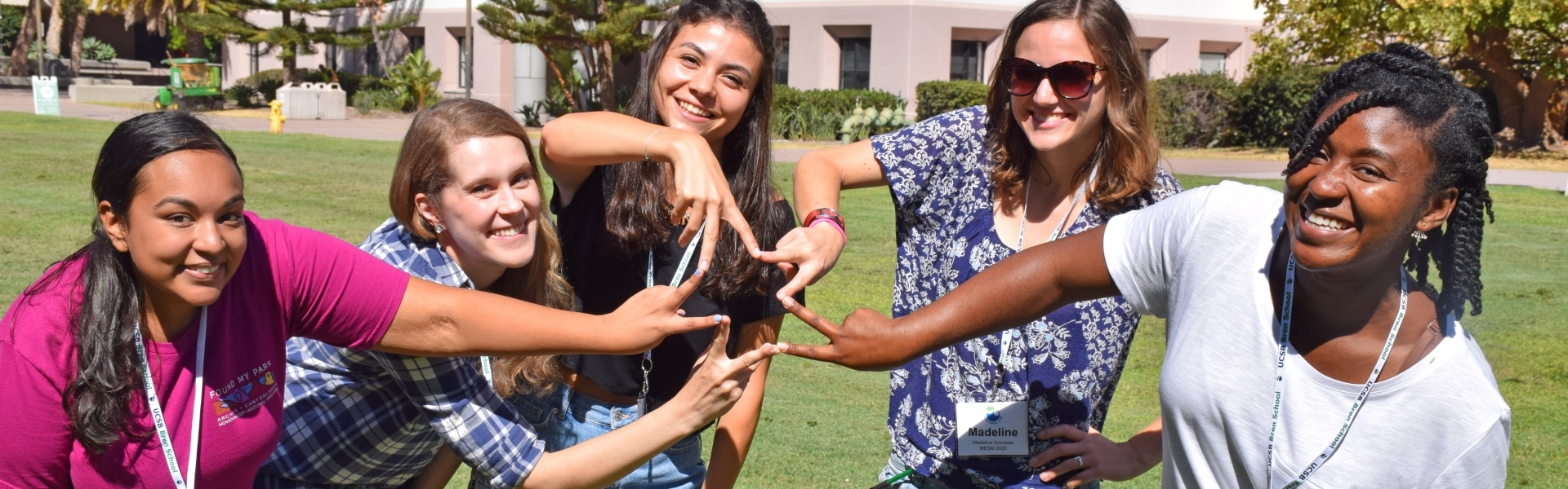 Group of five students making peace signs and smiling