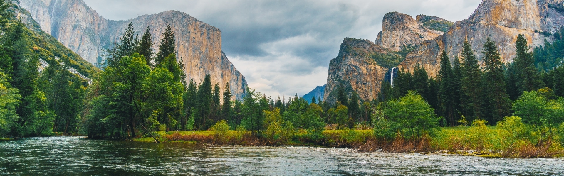 River flows by trees and Yosemite mountains