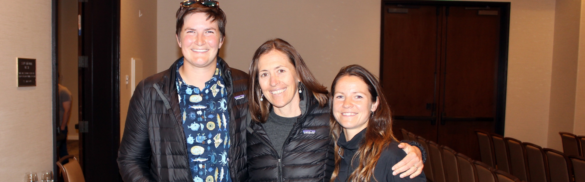 Three people pose together smiling