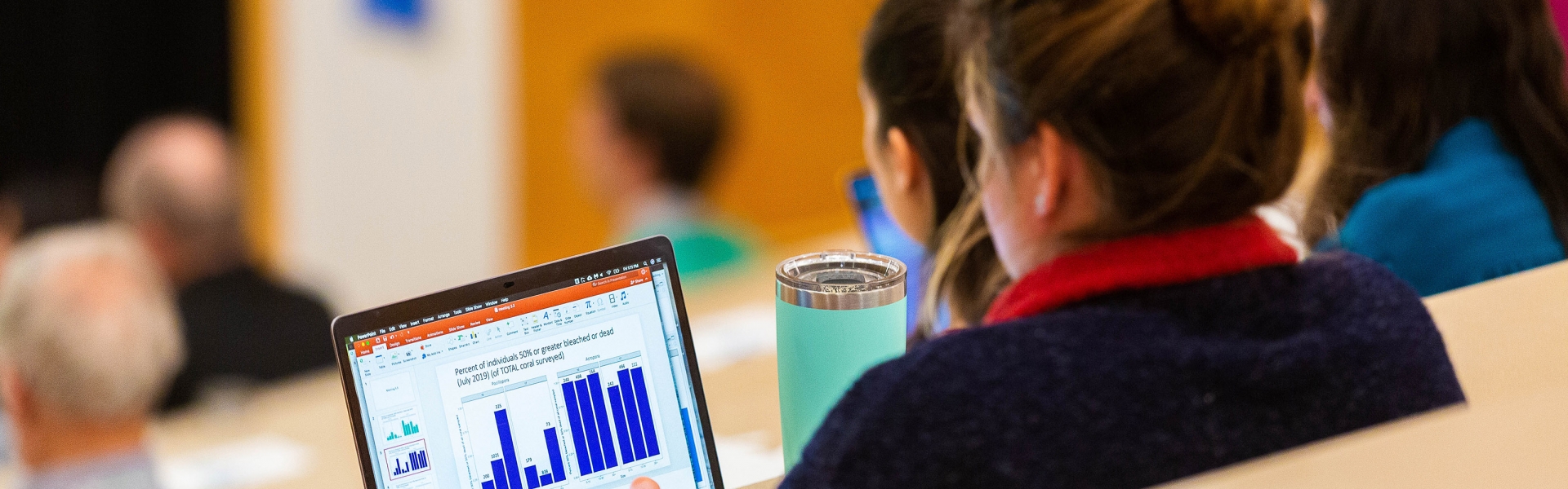 Student sitting in lecture hall working on laptop