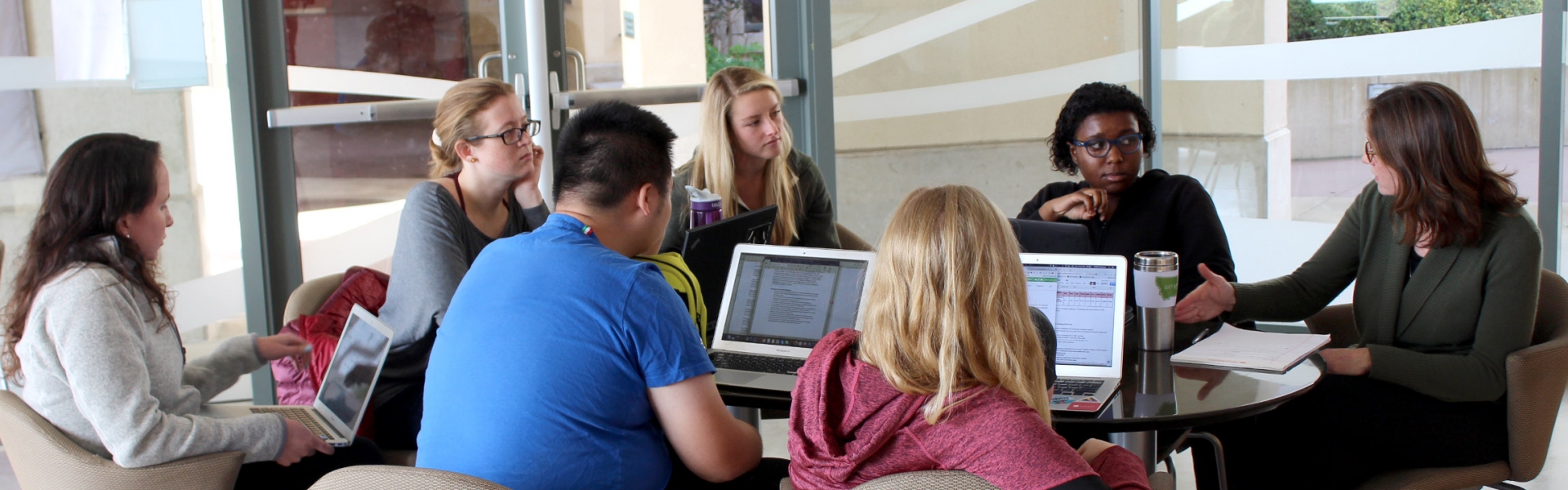 Group of students sitting at table listening to faculty speak