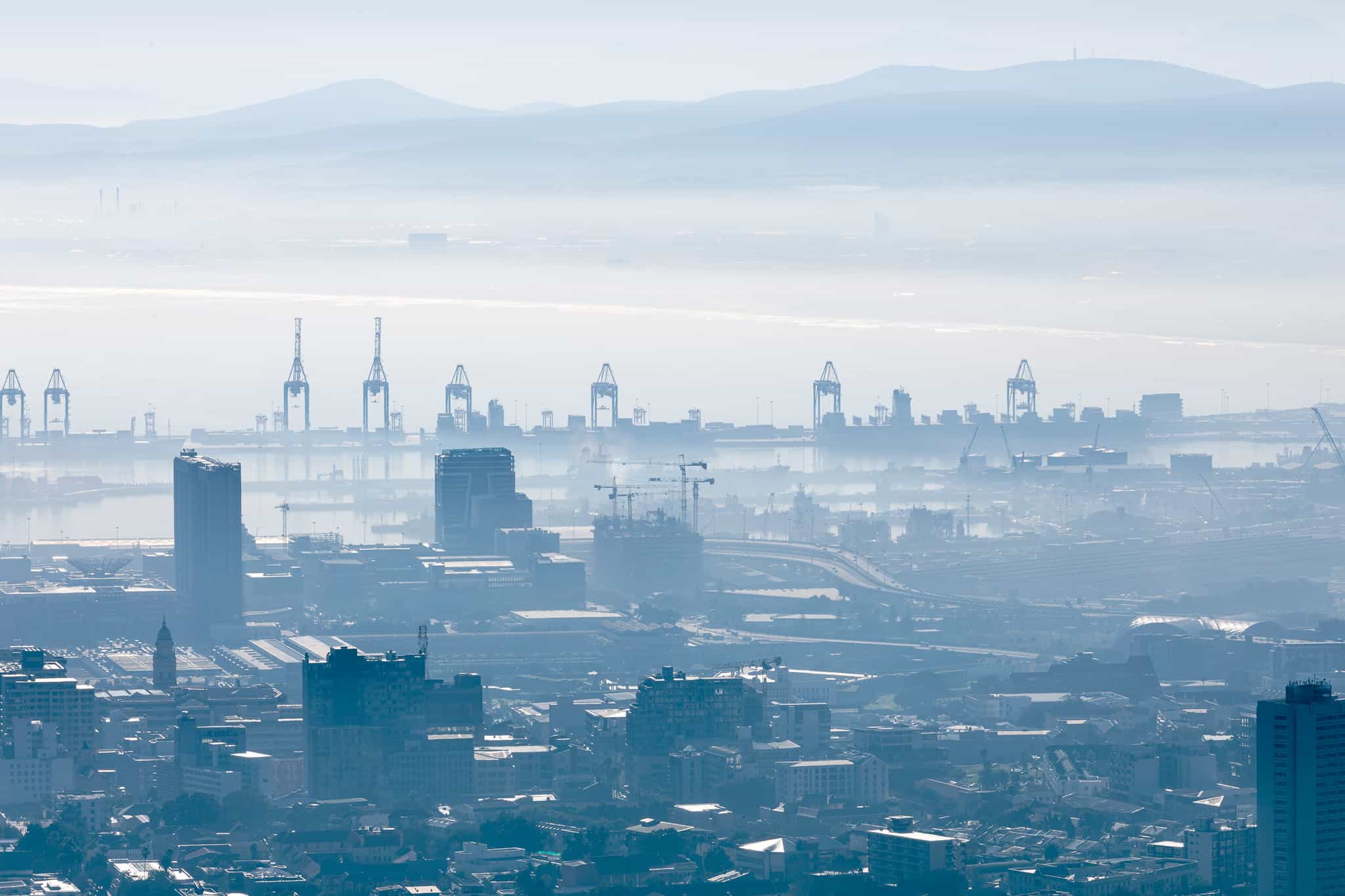General view of cityscape with multiple modern buildings and cranes in the foggy morning