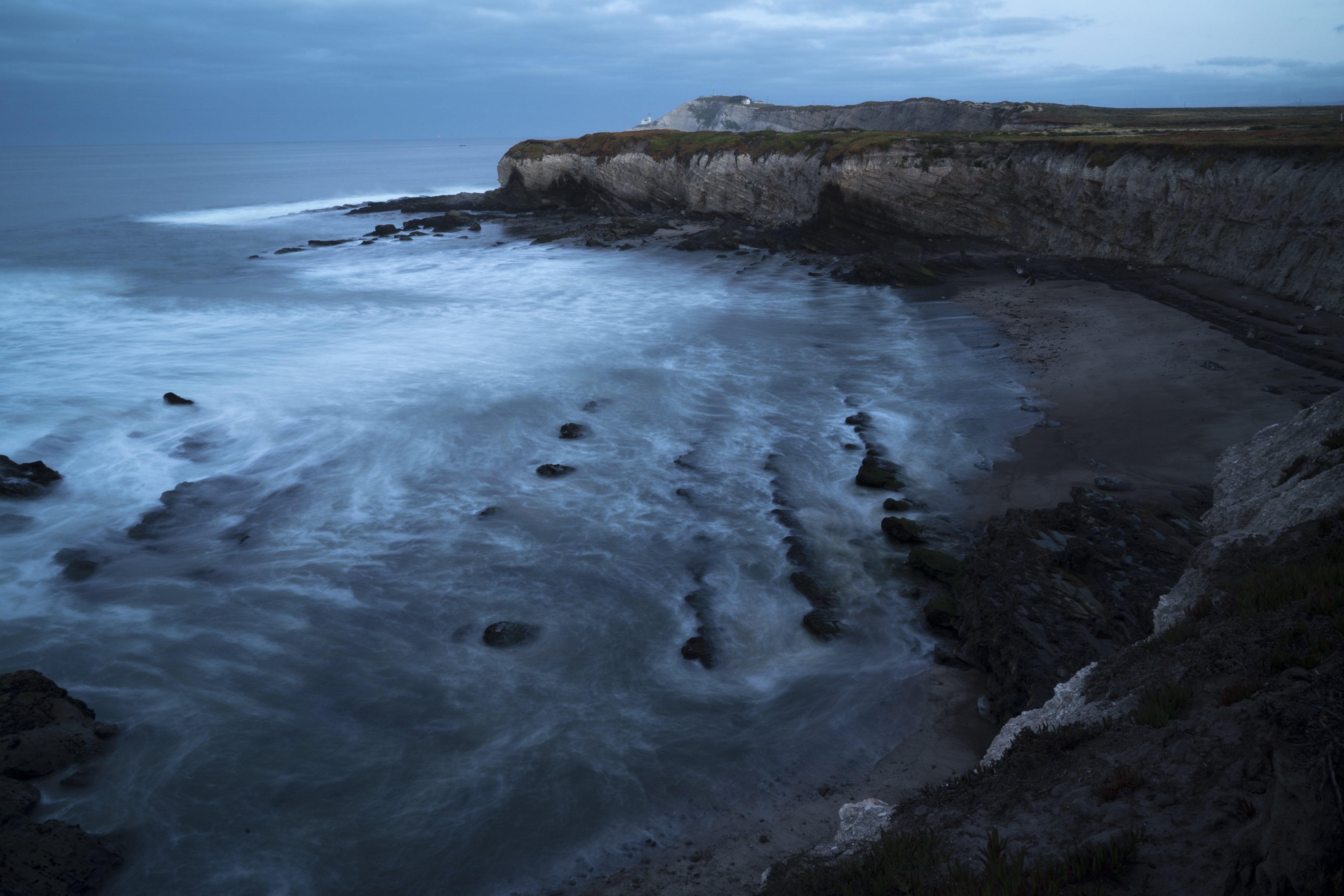 Coastal california scene with dark clouds, waves, rocky beach and cliffs