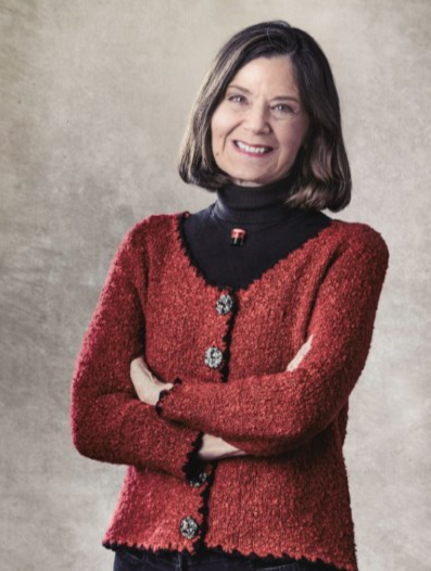 Lynn Scarlett wears a red jacket in front of a neutral backdrop