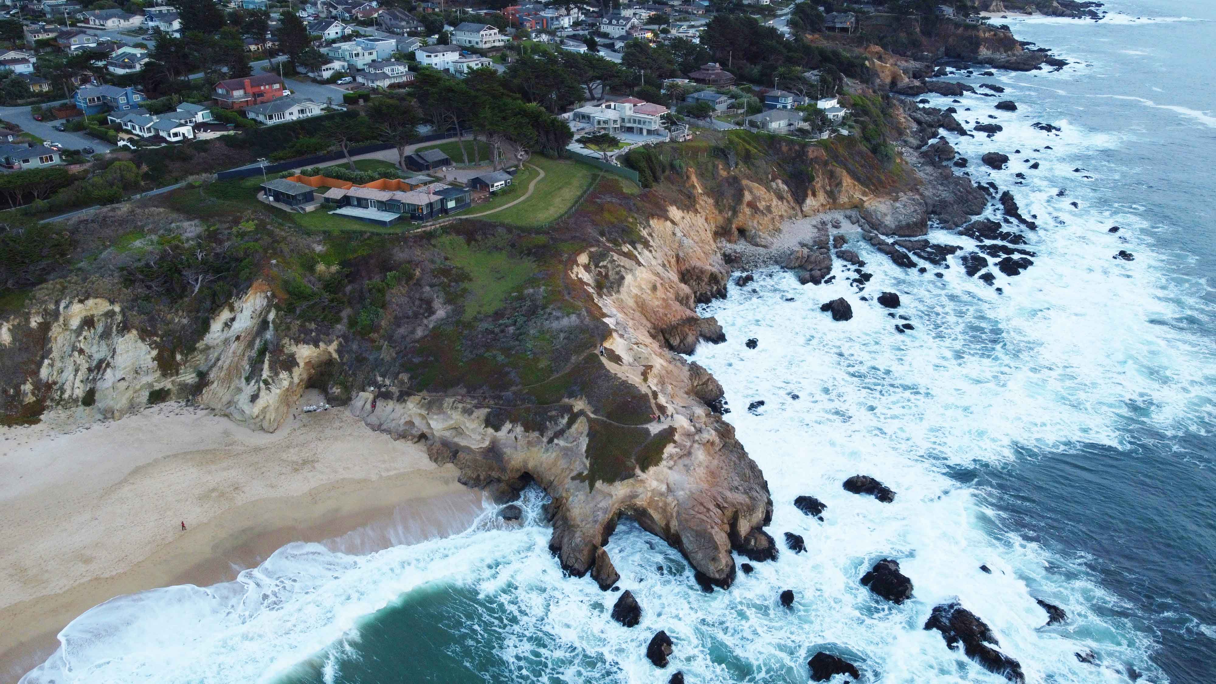 Shoreline with ocean and houses on top of cliffs