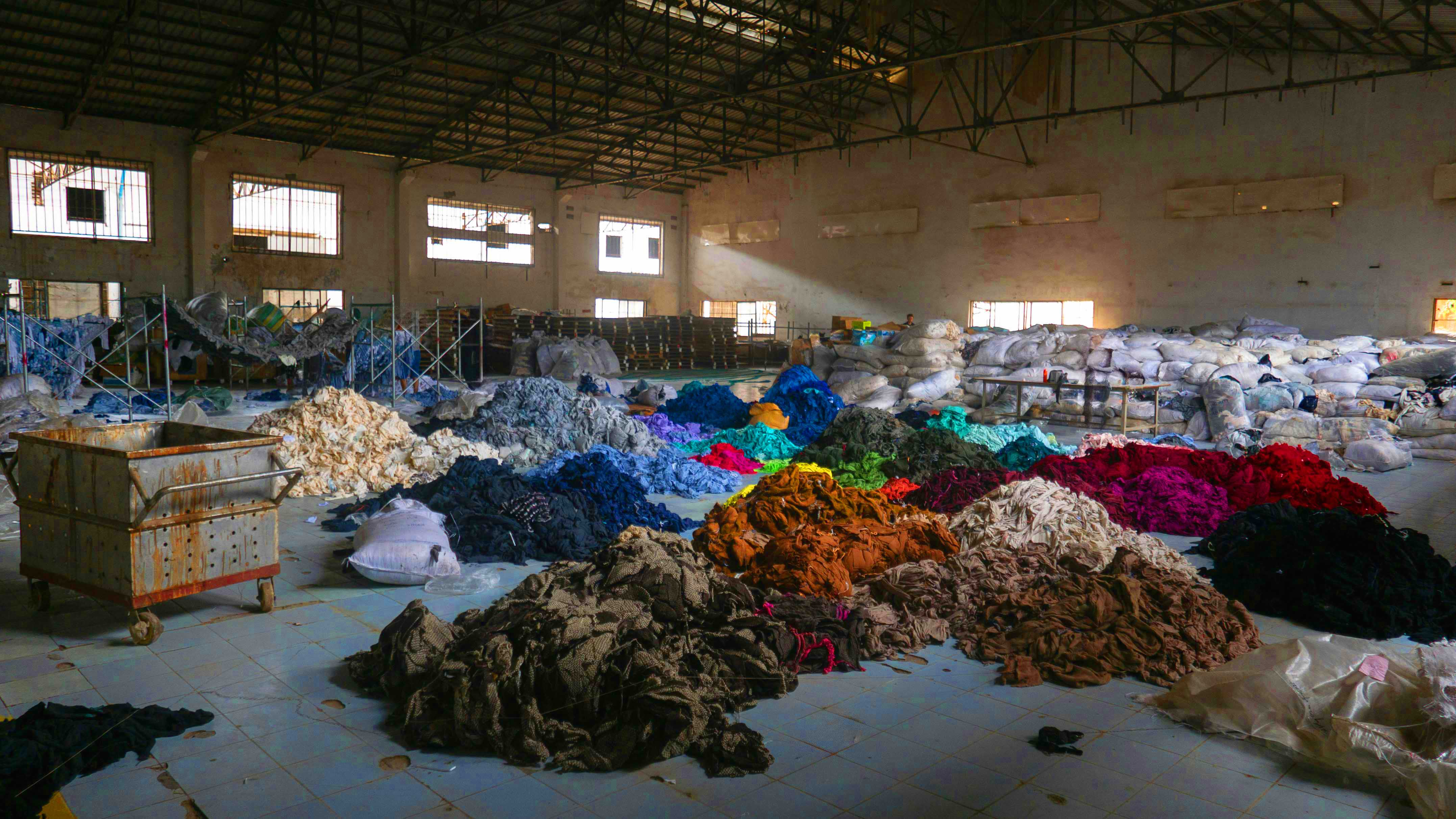 Clothing in piles on the floor of a warehouse