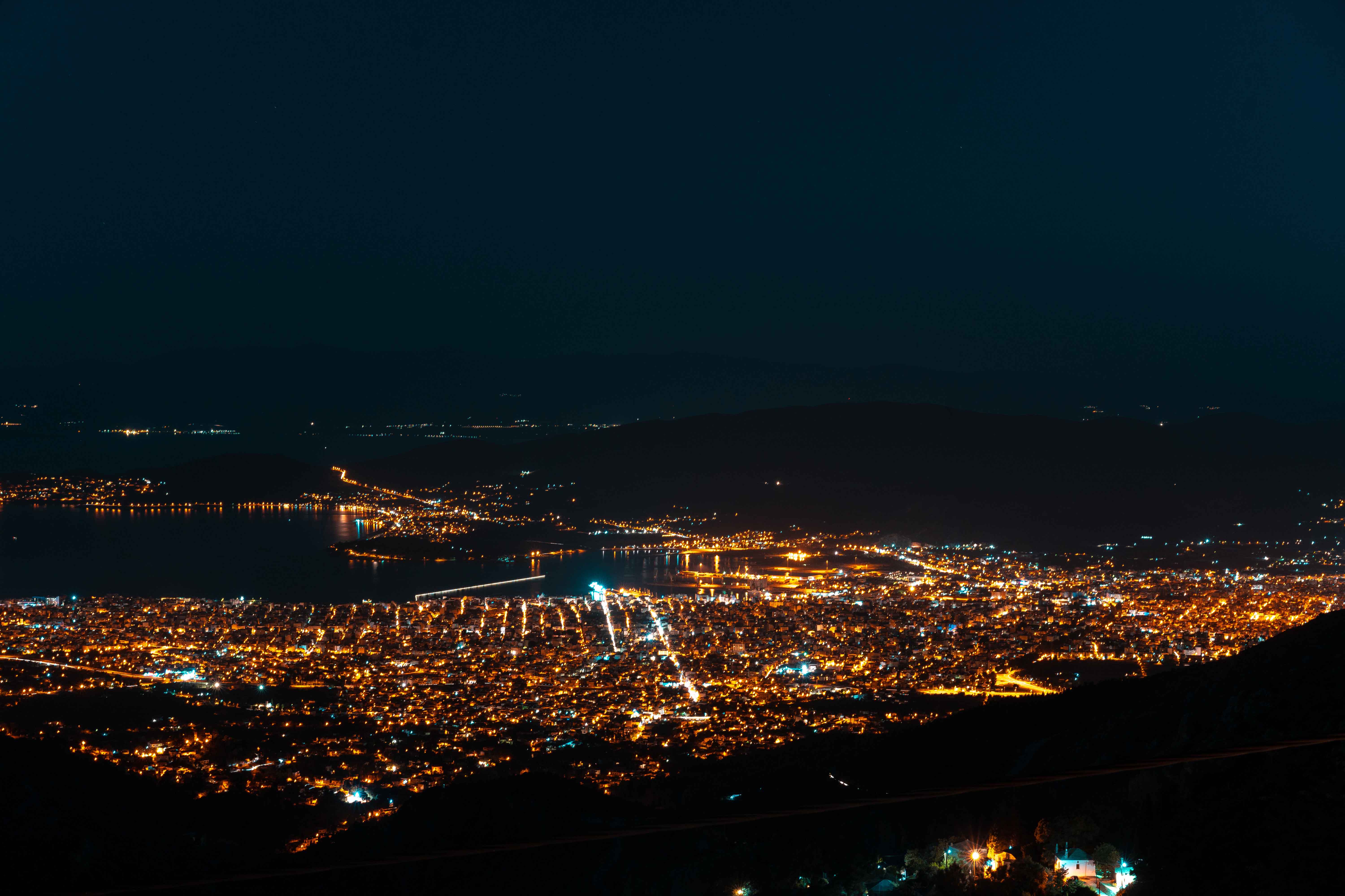 Aerial photo of a city near water at night time illuminated with lights