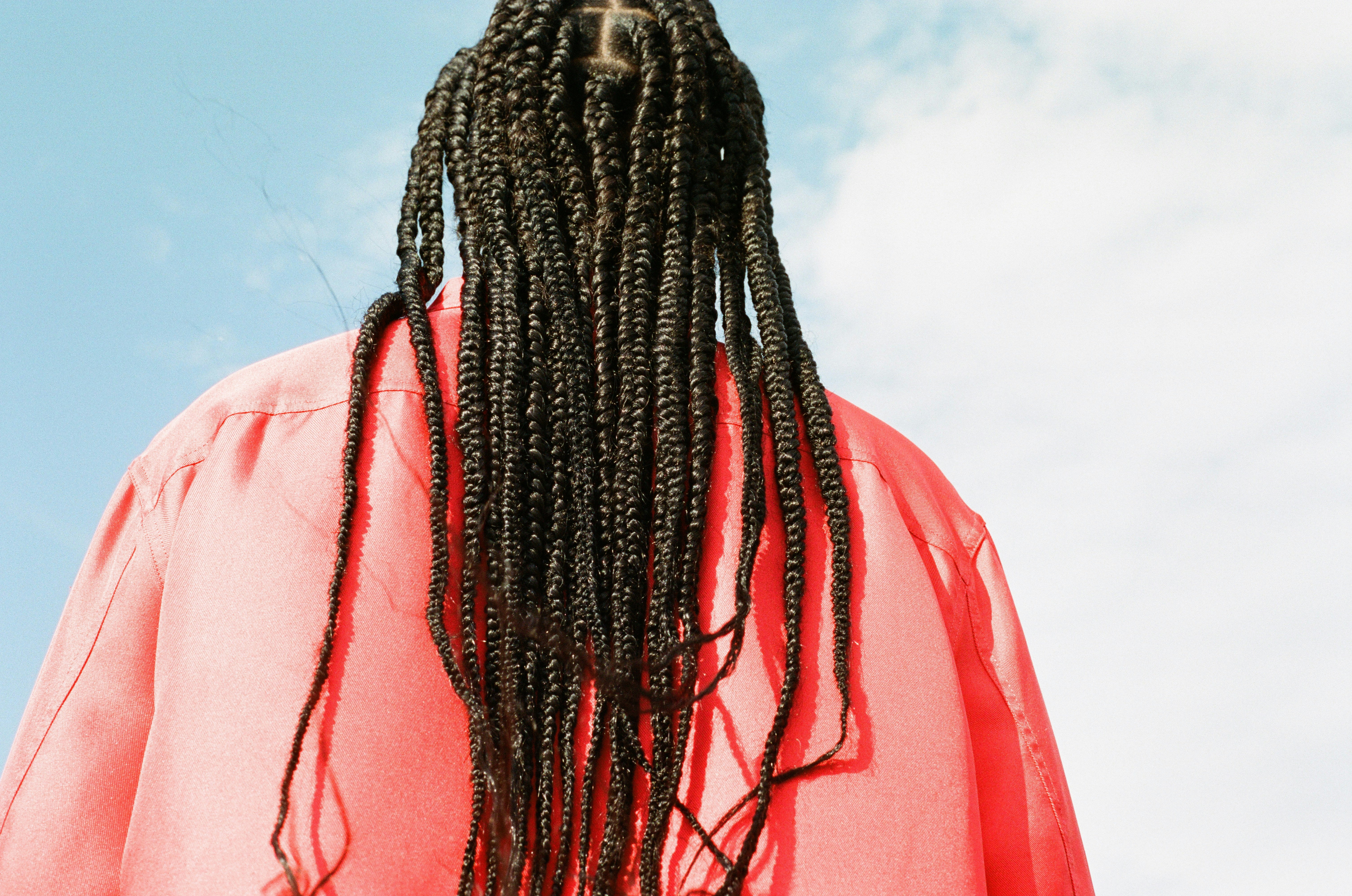 a person with braided hair looking up at the sky