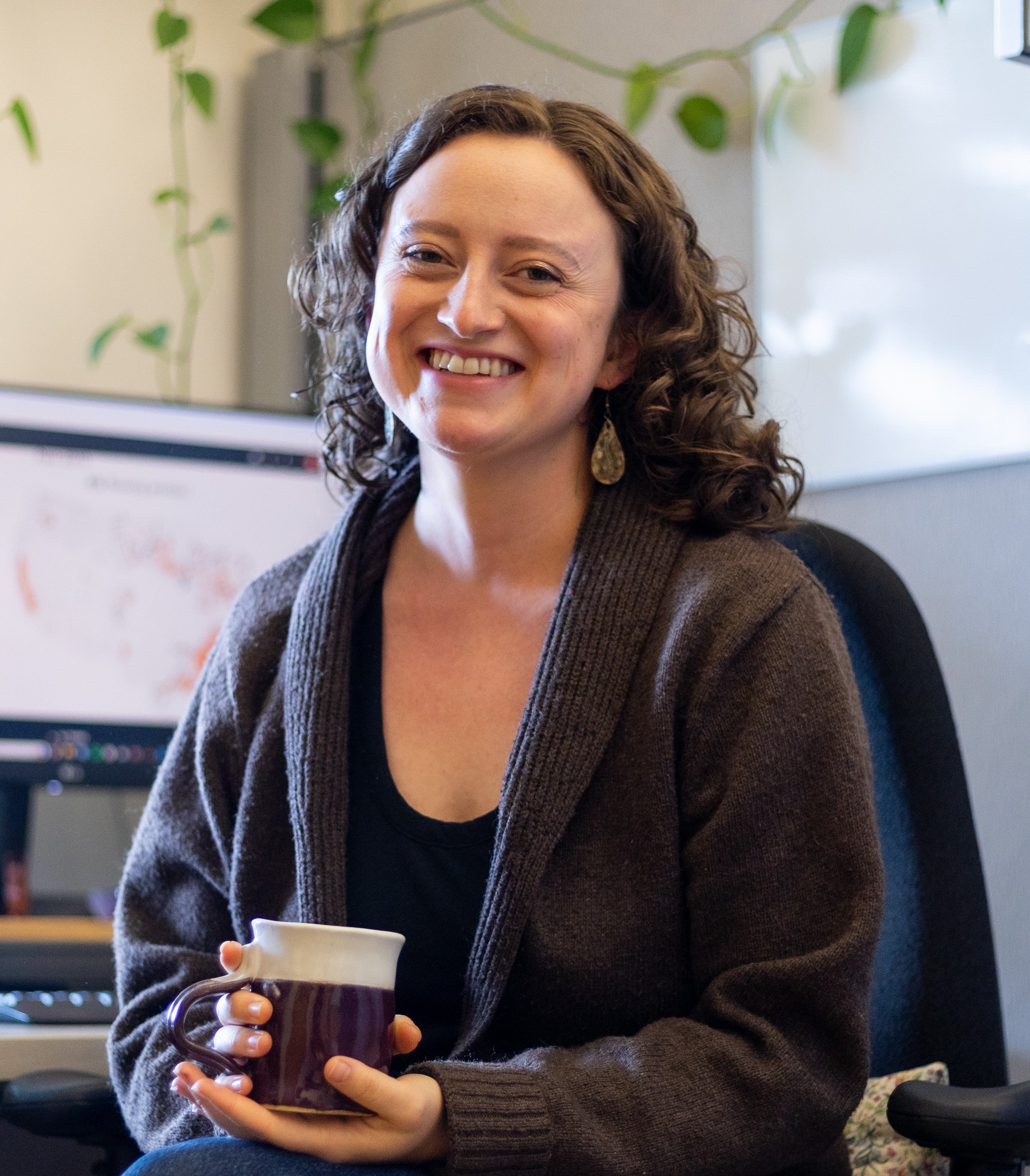 Annette Hilton sits in an office holding a mug of tea