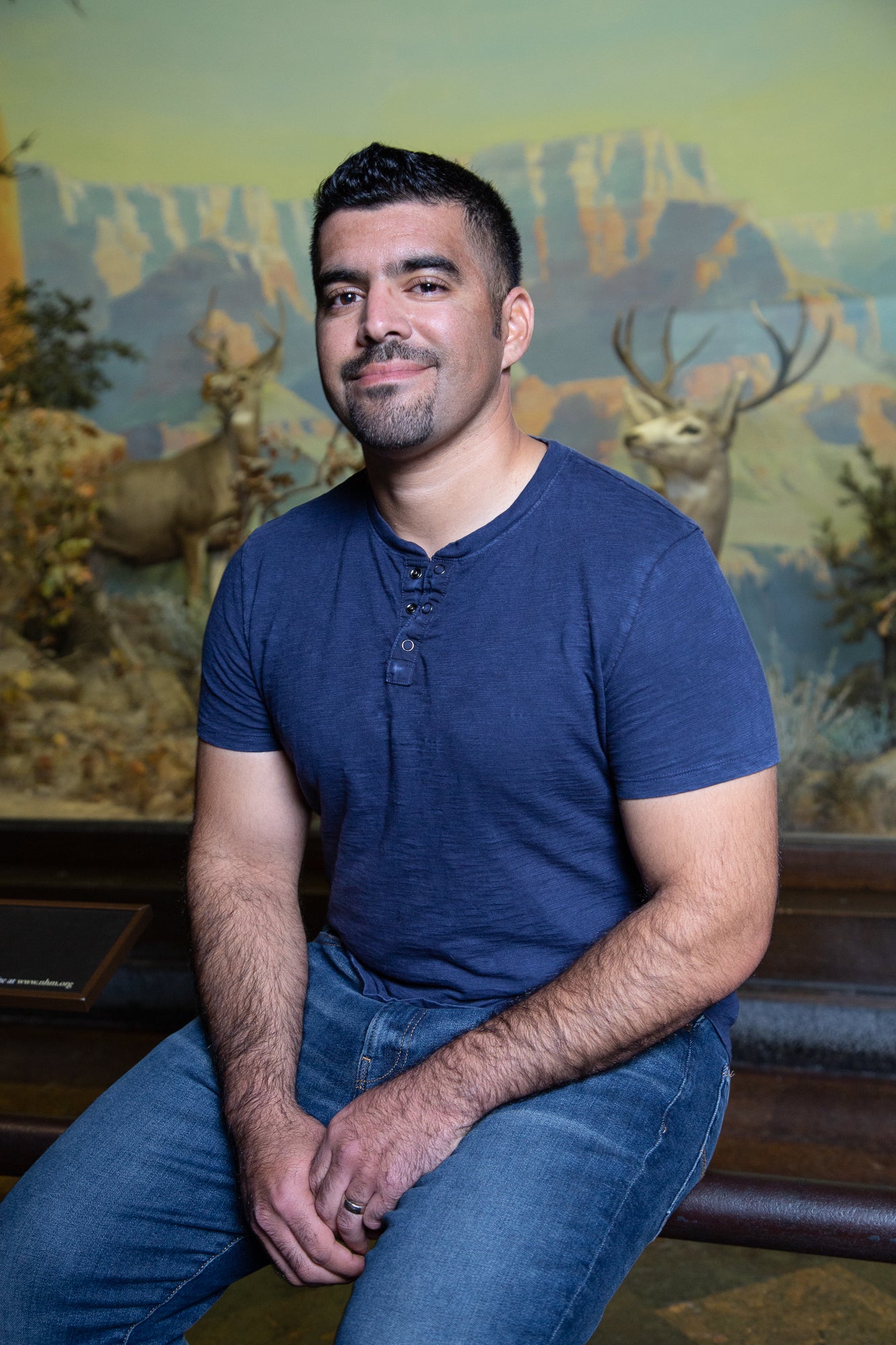 Miguel Ordenana sits in front of a mural