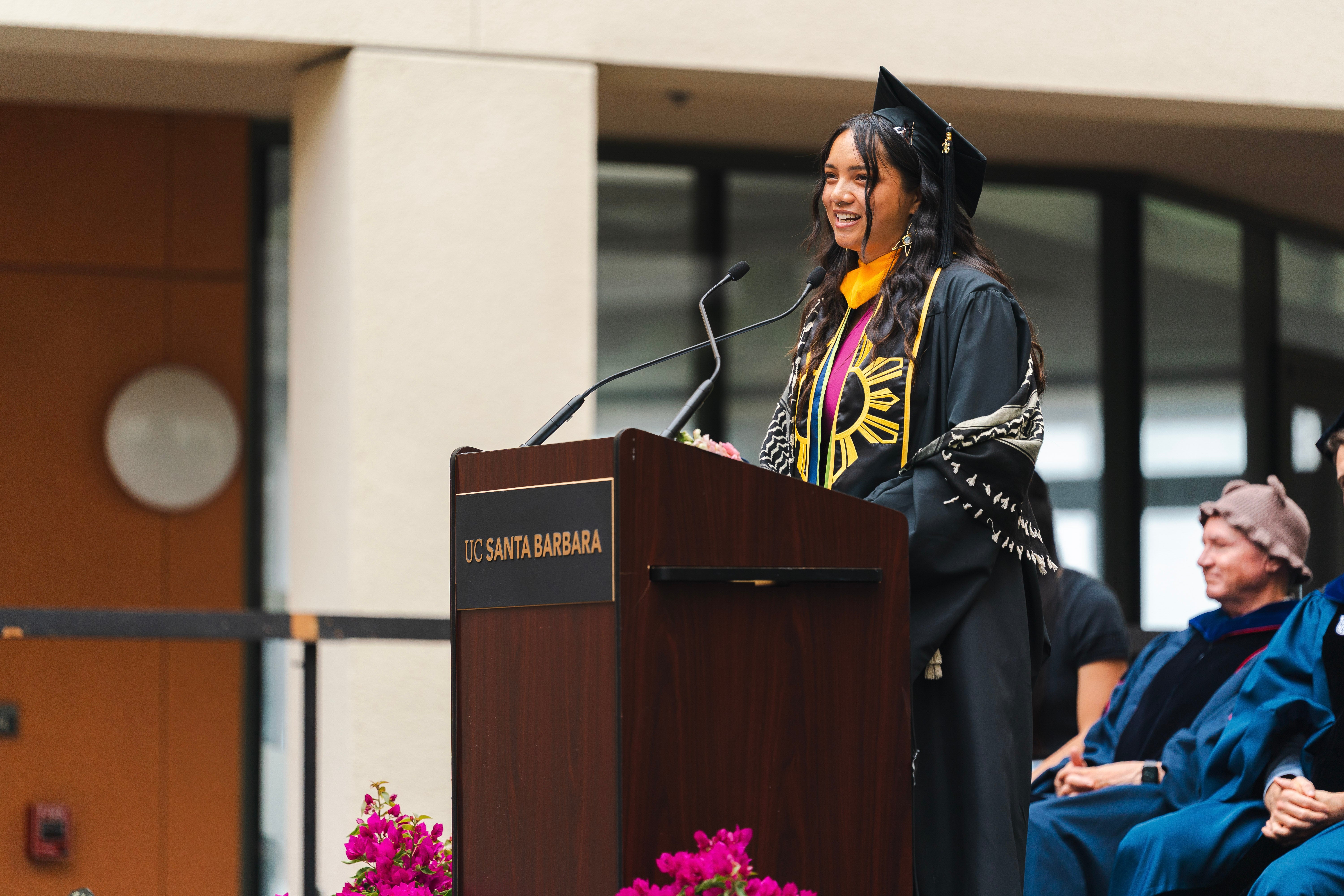 Lenaya-Aiden Gonzales speaks at the lectern during Bren commencement