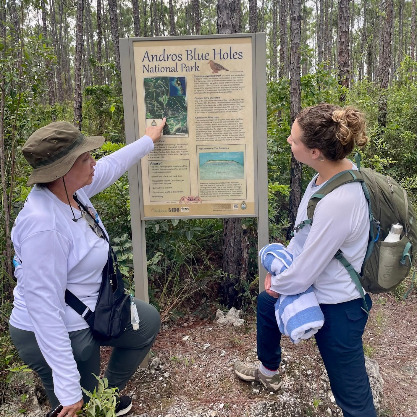 two women stand in nature discussing a sign