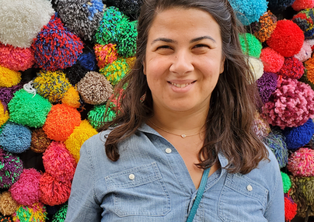 Smiling woman stands in front of colorful background