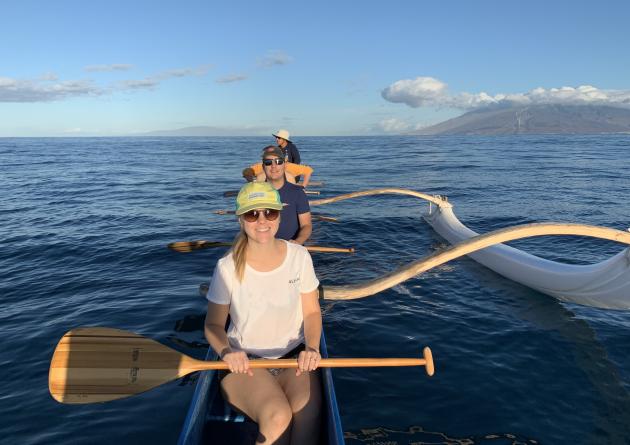 Woman and two men canoeing in ocean